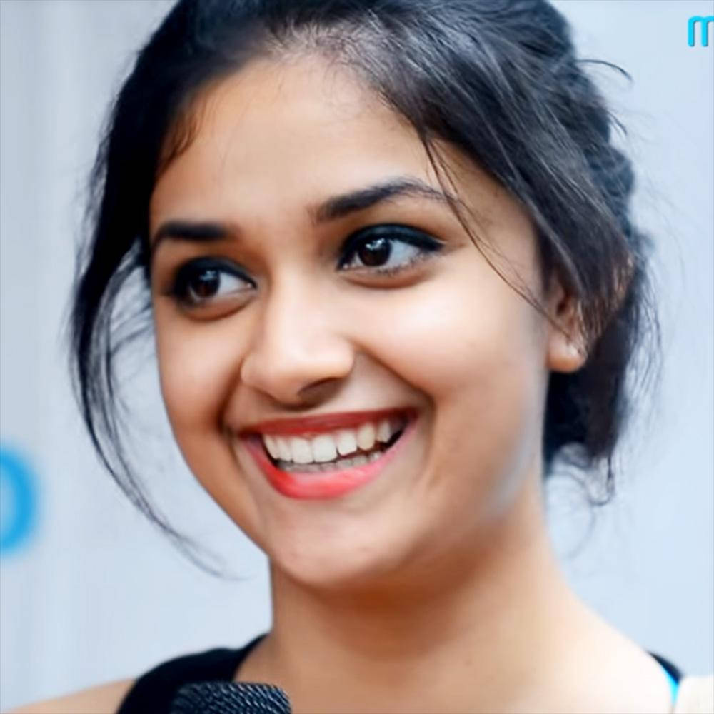 Keerthi Suresh HD 桌布 壁紙 — 一位黑髮、塗著鮮紅色唇膏的微笑女士的近距離特寫，視線望向鏡頭外。