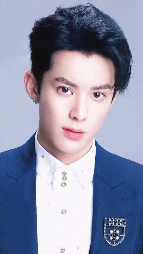 Dylan Wang 桌布 壁紙 — 一位黑髮、神情嚴肅的年輕男子身穿海軍藍西裝外套，內搭白襯衫，並別有裝飾胸針。