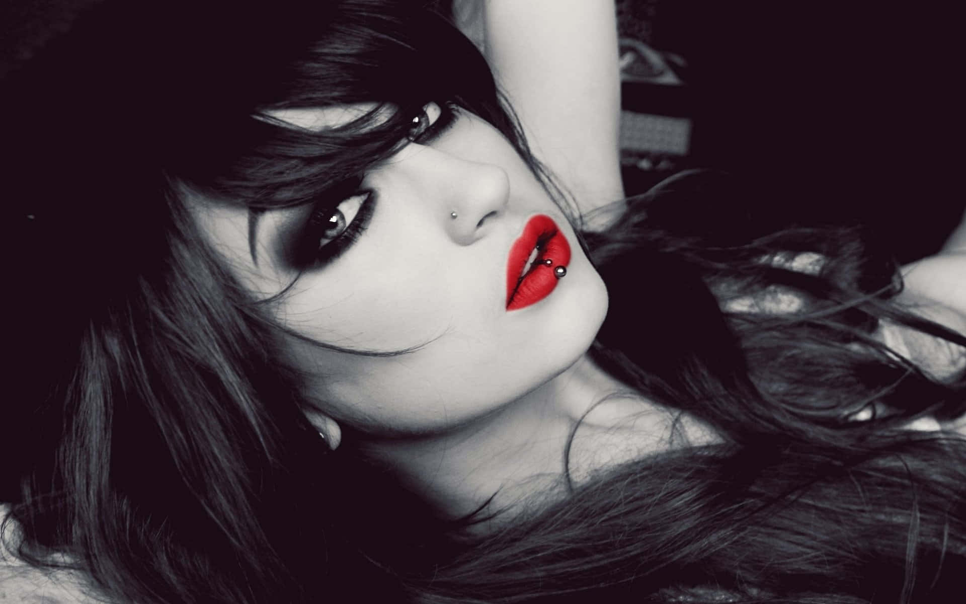 lipstick 桌布 壁紙 — 一位黑髮、紅唇大膽的女性，在黑白背景下凝視著。