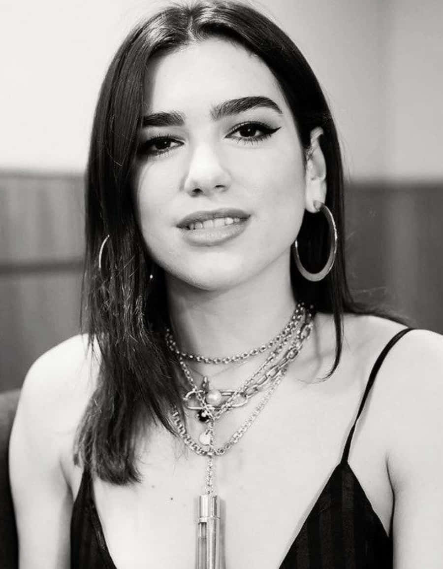 Dua Lipa 桌布 壁紙 — 一位黑髮女性戴著多層項鍊和大圈耳環的黑白肖像。