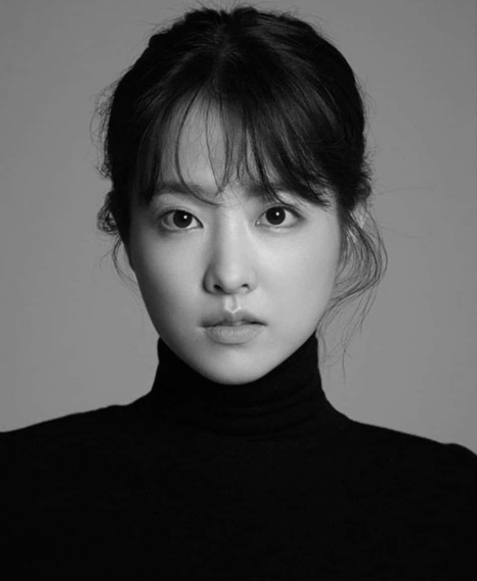 Black And White Celebrity 桌布 壁紙 — 一位黑髮年輕女性穿著高領毛衣，面無表情地直視鏡頭的黑白肖像。