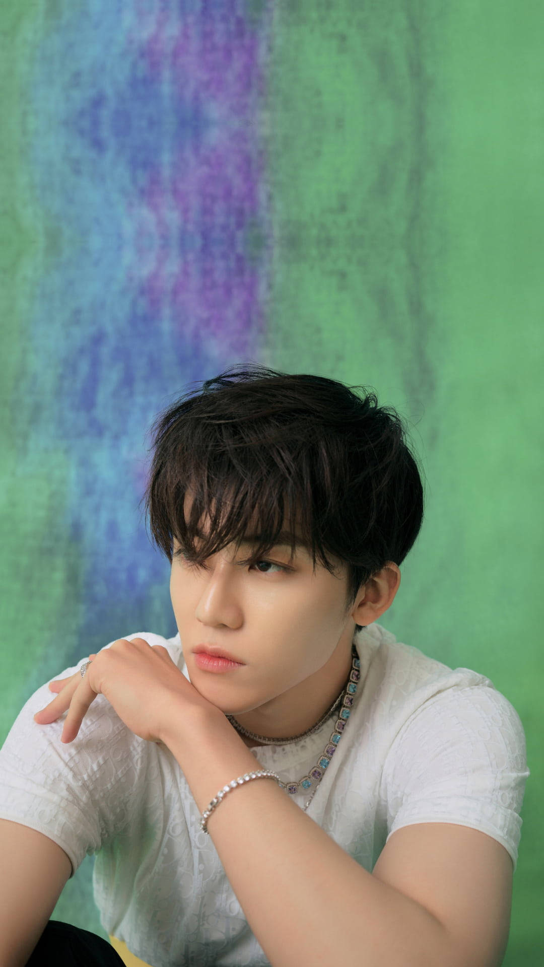 jaemin 桌布 壁紙 — 一位黑髮年輕男子將下巴靠在手上，背景是充滿活力的綠色和紫色紋理。
