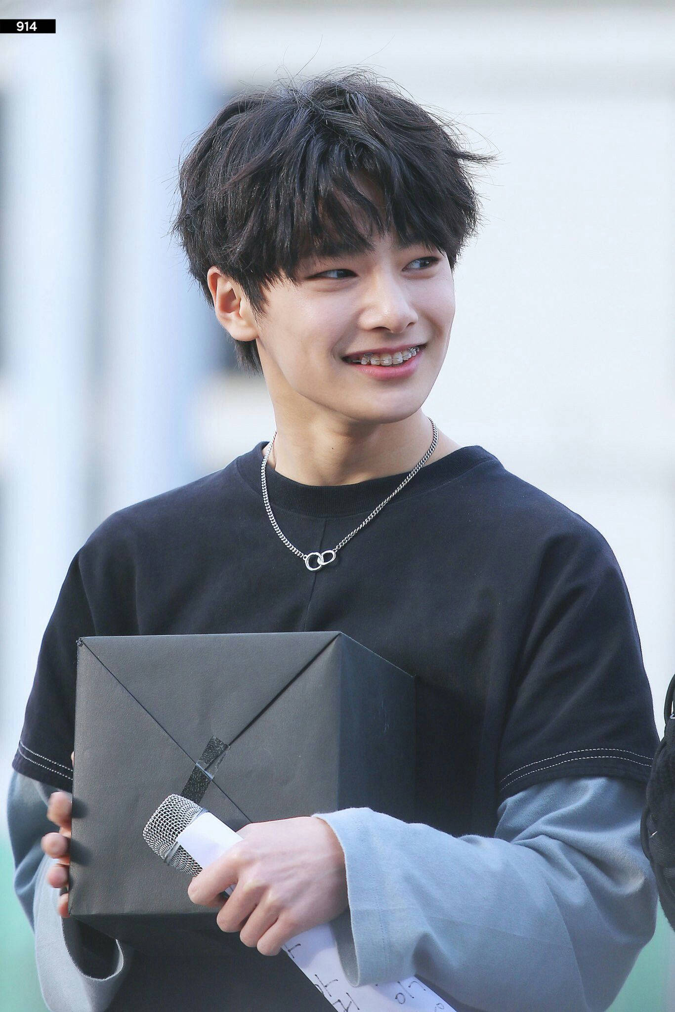 Stray Kids 桌布 壁紙 — 一位黑髮年輕男子微笑著，手持麥克風和黑色信封。