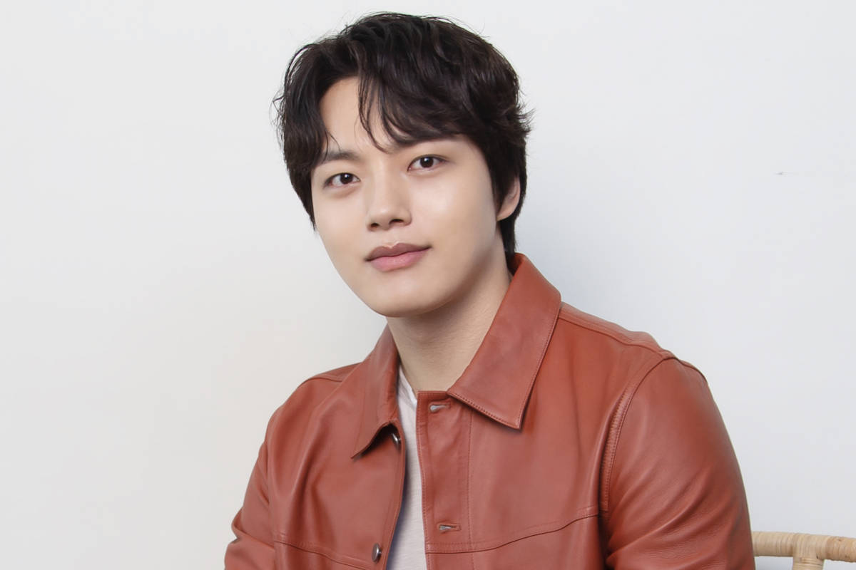 Jin 桌布 壁紙 — 一位黑髮年輕男子穿著棕色皮夾克，背景為純白色。