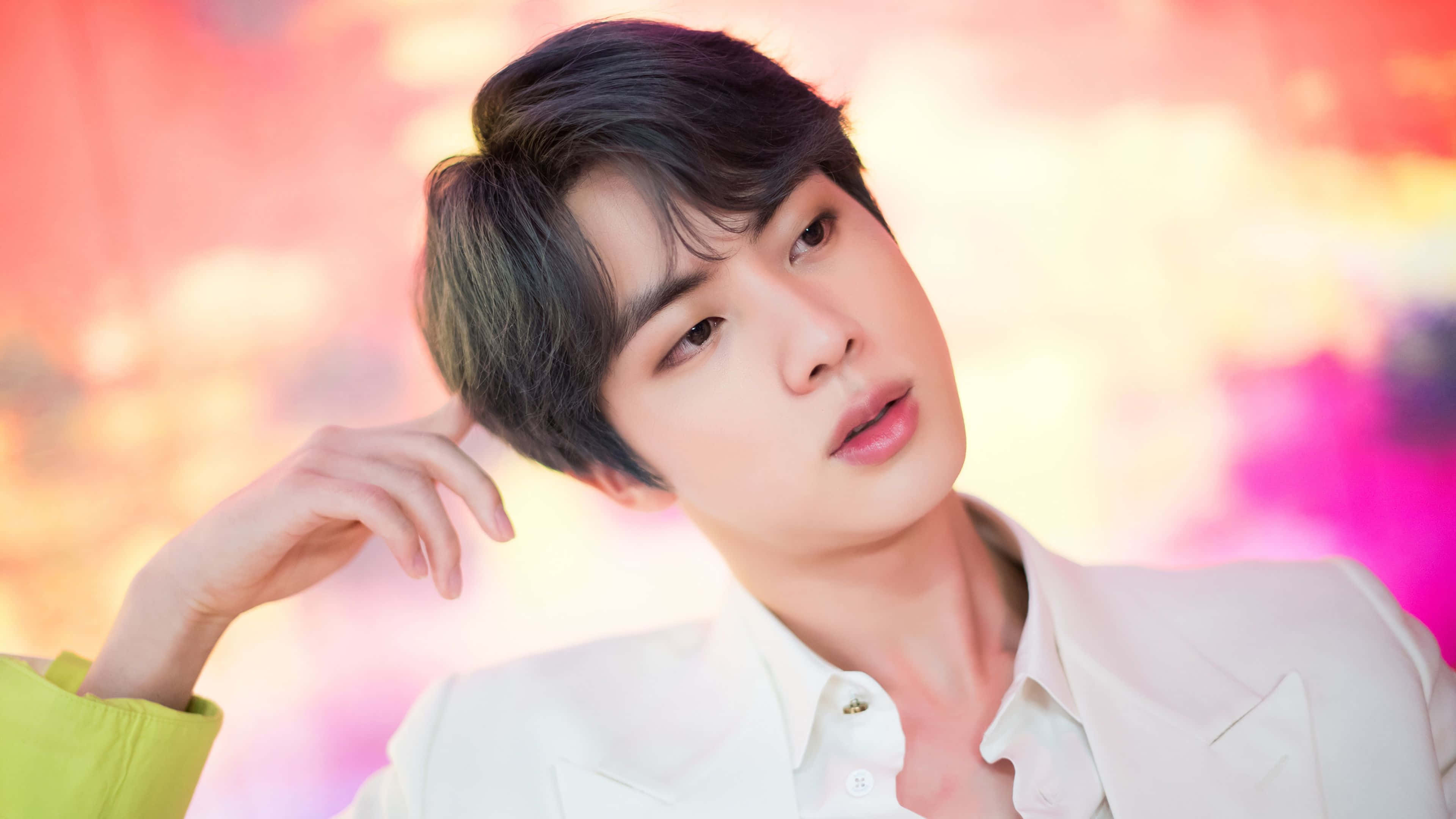 Jin 桌布 壁紙 — 一位黑髮年輕男子穿著白襯衫，在充滿活力的粉紅色和橙色模糊背景前擺姿勢。