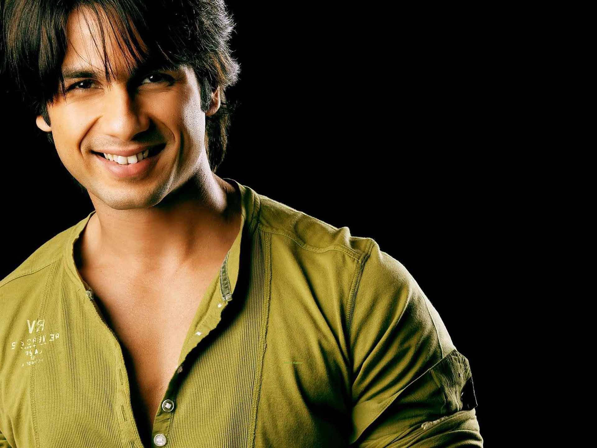 Shahid Kapoor 桌布 壁紙 — 一位黑髮微笑的男子穿著橄欖綠襯衫，背景為黑色。