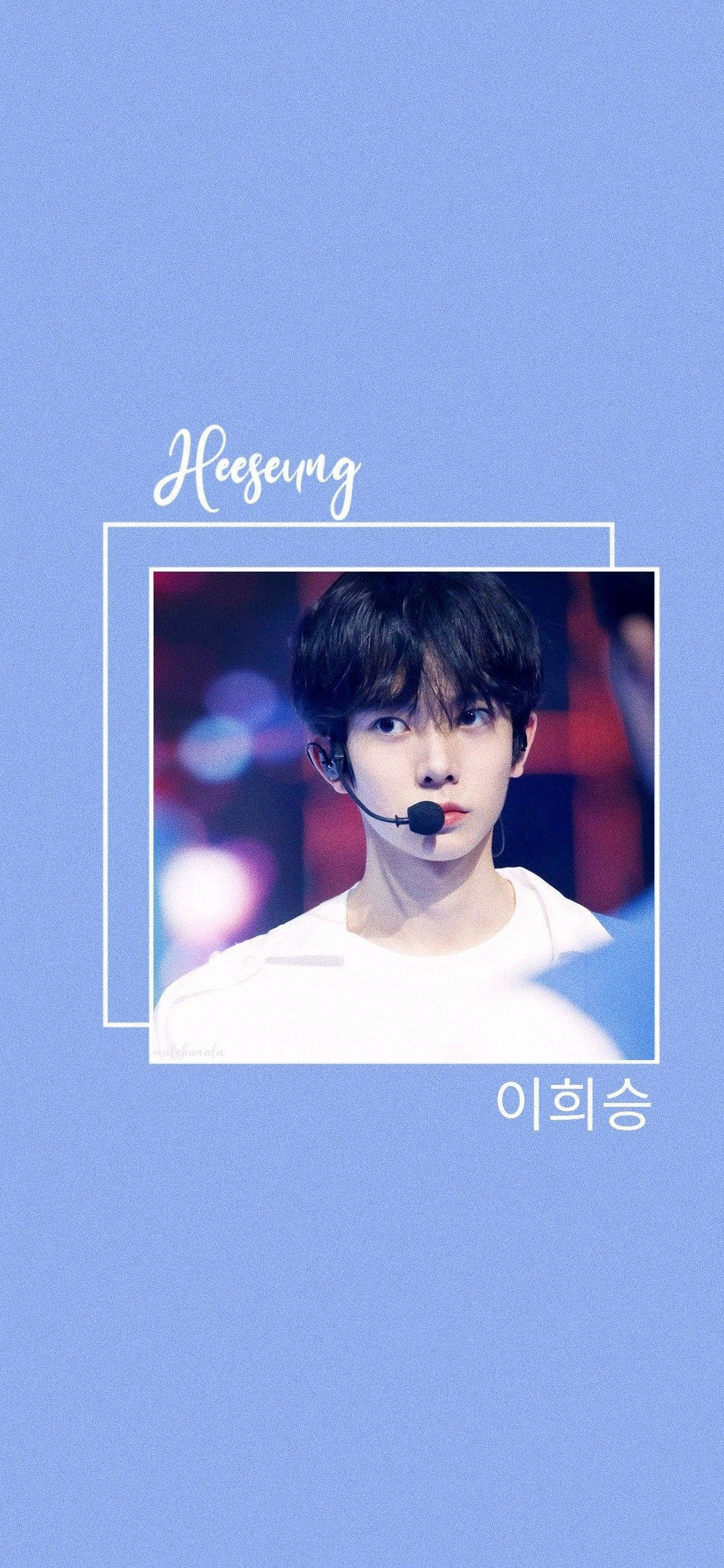 Kpop Aesthetic 桌布 壁紙 — 一位黑髮戴耳機的年輕男子，在白色邊框框住的模糊舞台背景襯托下，於純藍色背景上溫柔微笑。