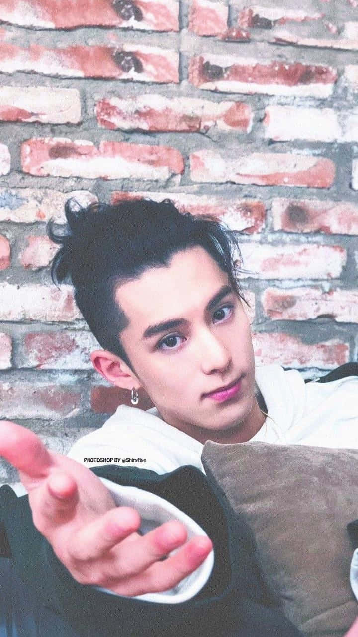 Dylan Wang 桌布 壁紙 — 一位黑髮戴耳環的年輕男子靠著風化的磚牆，向觀者伸出手。