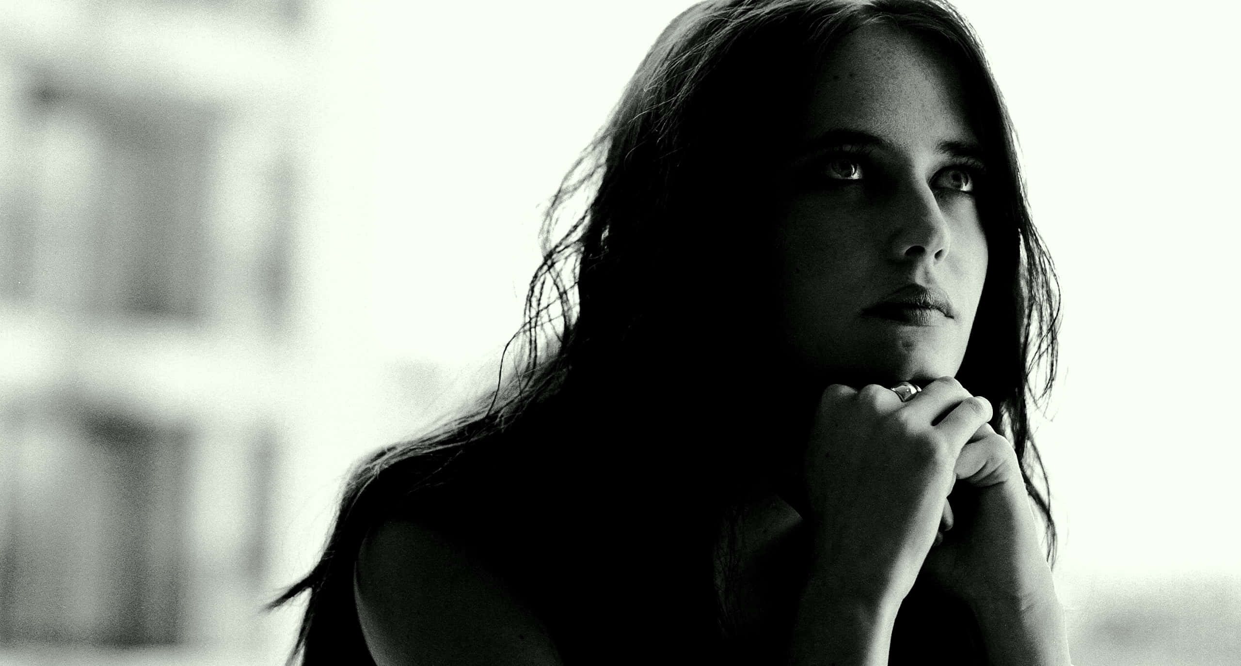 eva green 桌布 壁紙 — 一位黑髮的沉思女性在鮮明的黑白肖像中若有所思地向上凝視。