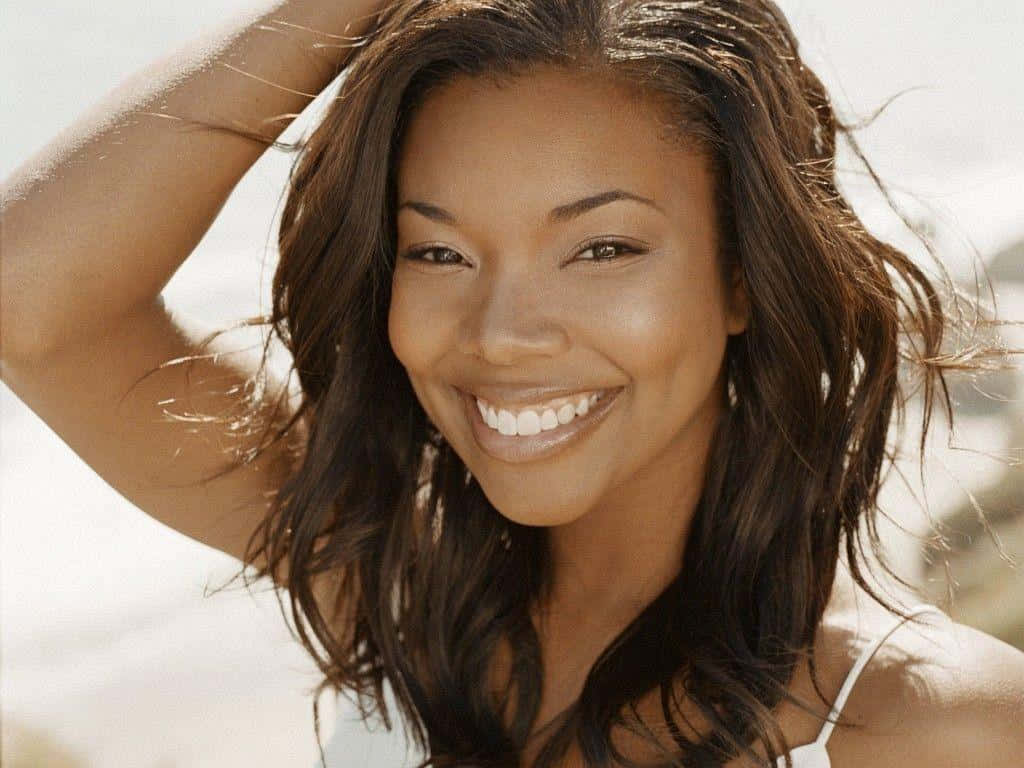 gabrielle union 桌布 壁紙 — 一位黑髮的燦爛女性在戶外陽光捕捉她喜悅表情時燦爛微笑。