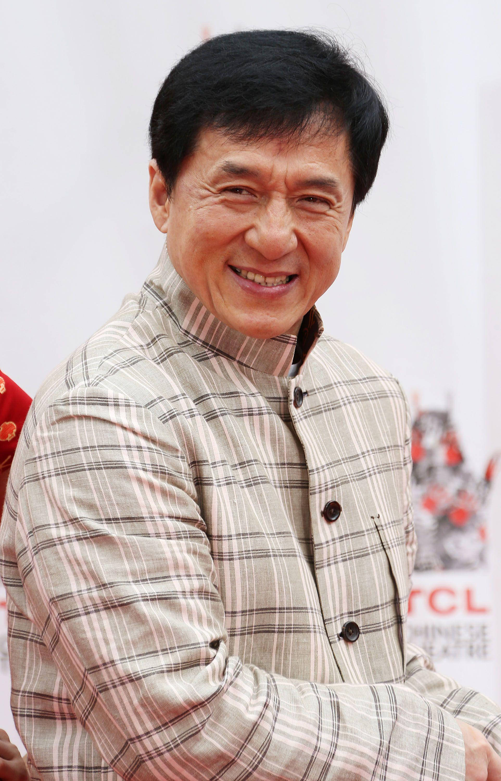Checkered 桌布 壁紙 — 一位黑髮的開朗男士在活動中穿著米色格紋鈕扣襯衫，溫暖地微笑。