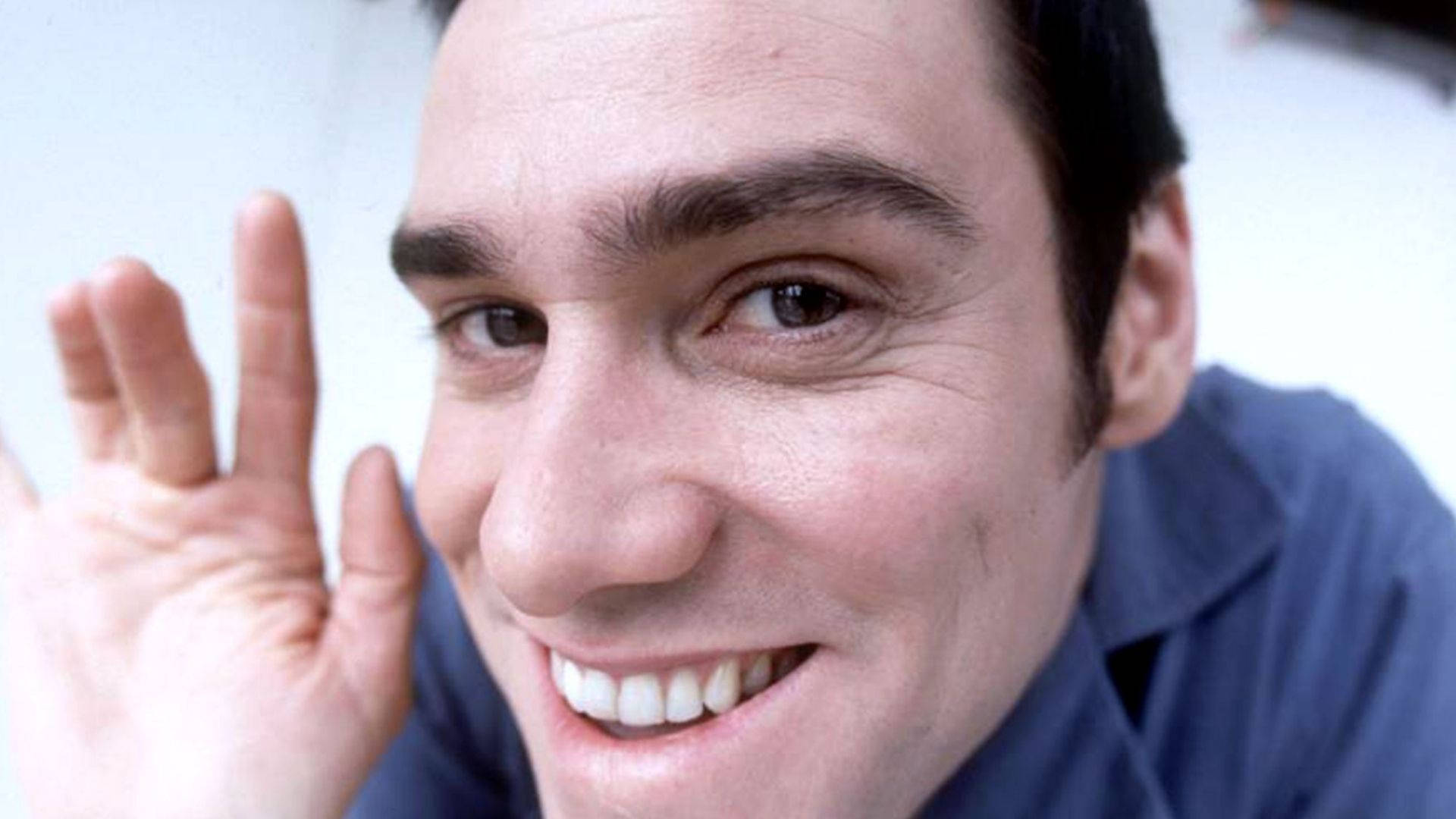 Jim Carrey 桌布 壁紙 — 一位黑髮的開朗男子在特寫鏡頭中，微笑著向鏡頭揮手。