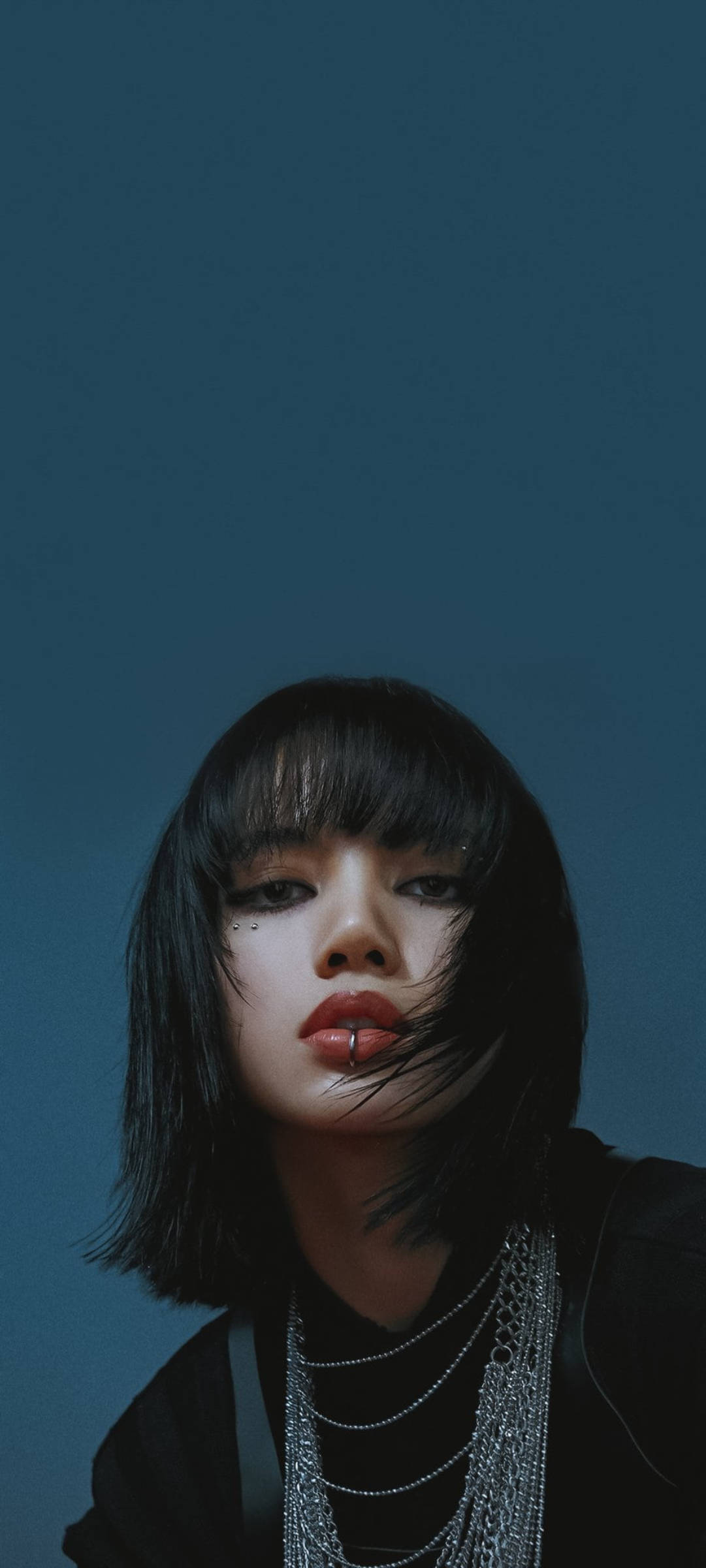 黑髮紅唇的年輕女性在藍色背景下佩戴層疊鏈條。 — BLACKPINK Lisa GIF 壁紙
