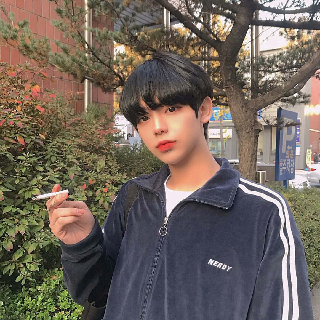 美少年動態圖 桌布 壁紙 — 一位黑髮紅唇的年輕男子，身穿帶有白色條紋的海軍藍天鵝絨外套，在戶外拿著一支香煙。