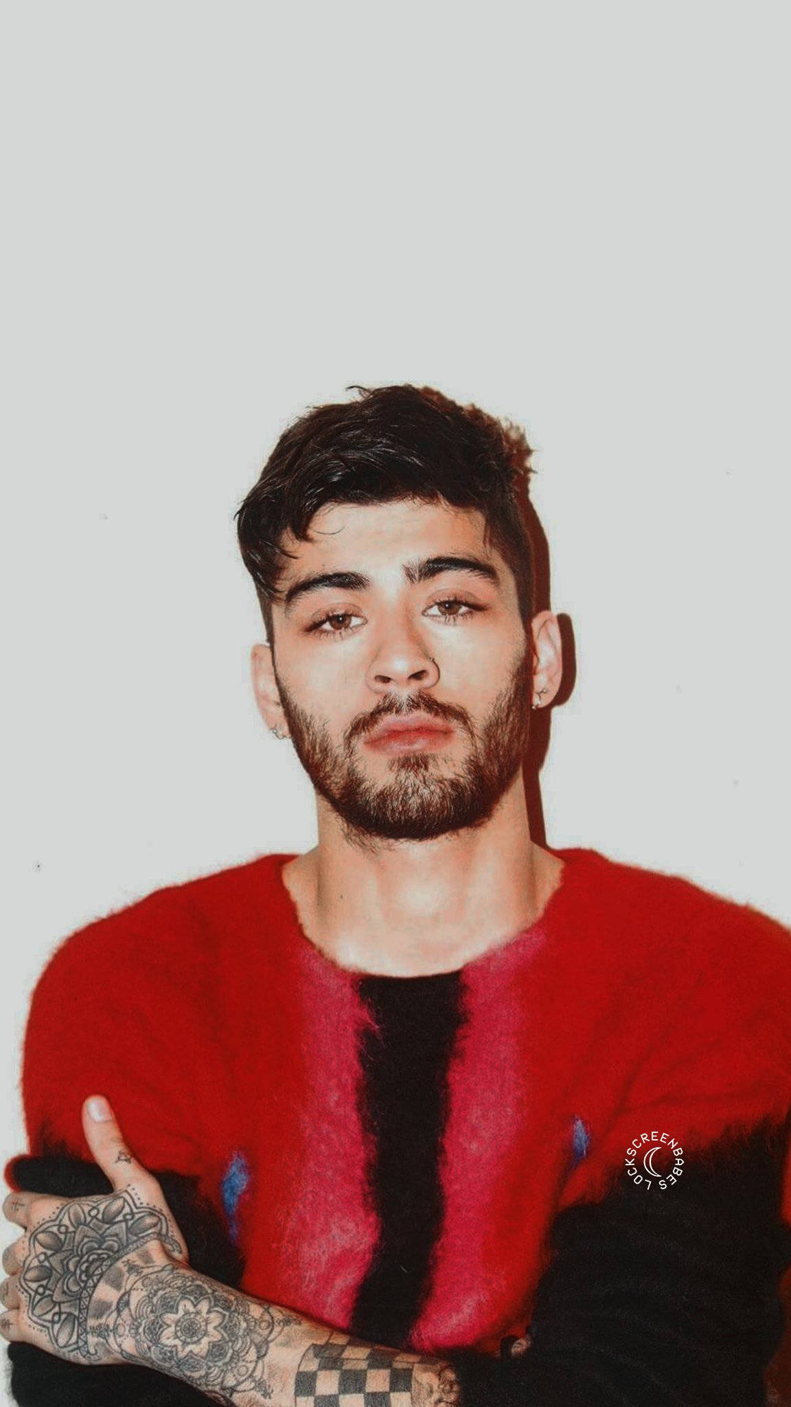 One Direction 桌布 壁紙 — 一位黑髮鬍鬚的年輕男子穿著紅黑絨毛毛衣，直視鏡頭，手臂上的刺青清晰可見。