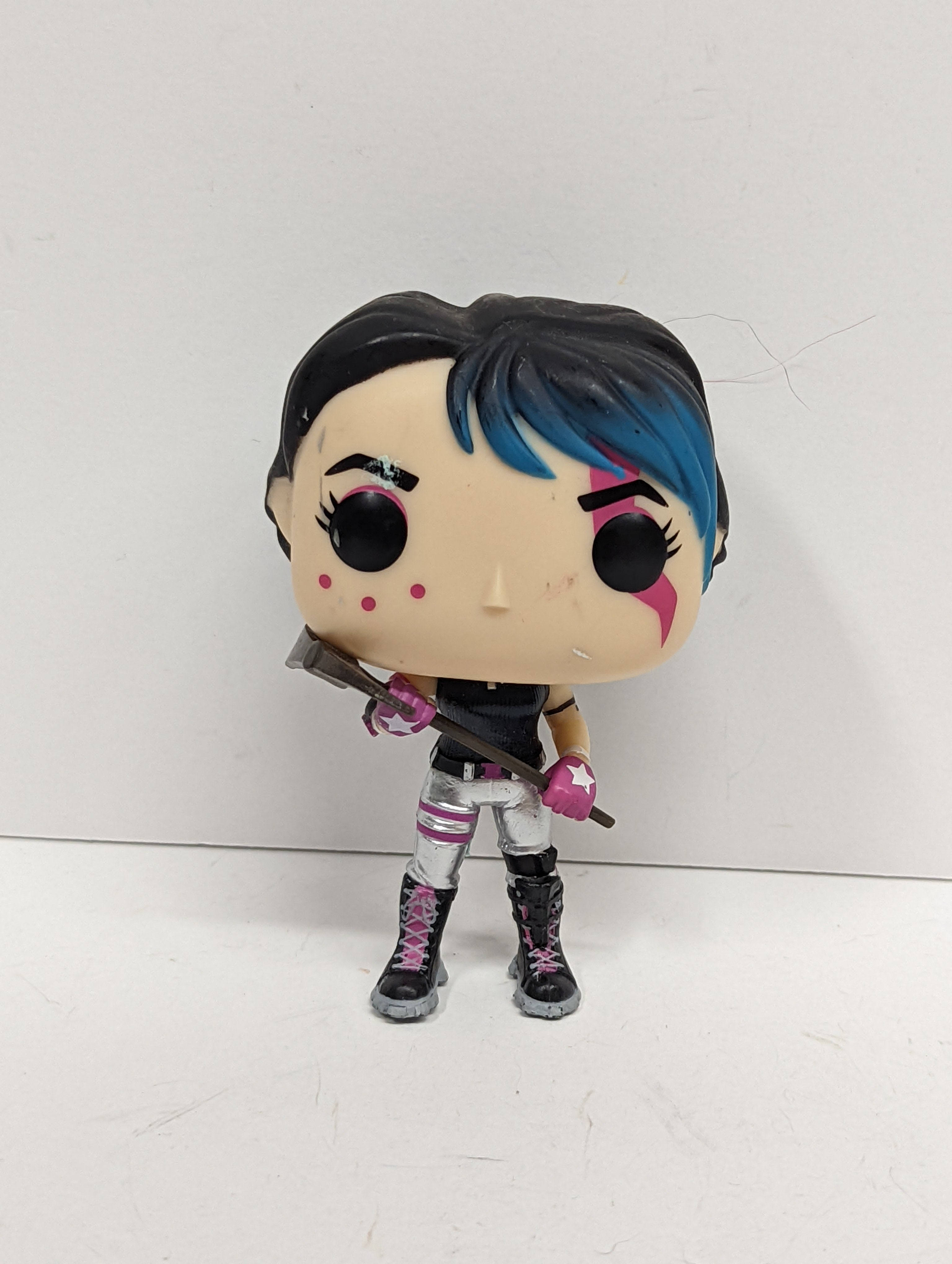 高清 桌布 壁紙 — 一個 Funko Pop! 公仔，描繪一個風格化的女性角色，擁有藍色和黑色頭髮、粉紅色臉部彩繪和武器，站在純白色背景前。