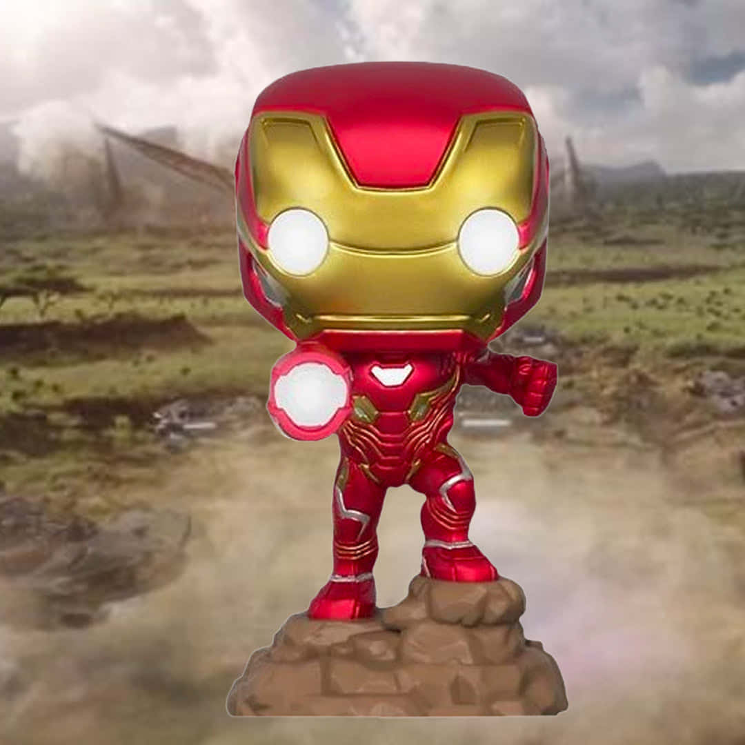 Iron Man Pop Figures 桌布 壁紙 — 一個 Funko Pop 鋼鐵人人偶站在岩石底座上，背景是煙霧瀰漫的戰場。