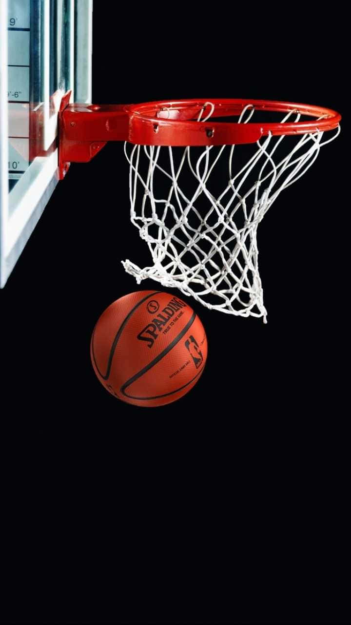 桌布 壁紙 — 一個 Spalding 籃球懸掛在紅色籃框正下方，背景為純黑色。