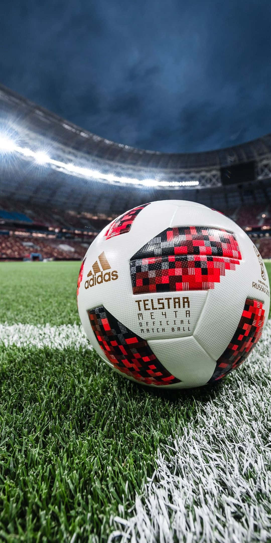 sport 桌布 壁紙 — 一個 Telstar Mechta 足球放在充滿活力的綠色草地上，上方是球場燈光和黑暗的天空。