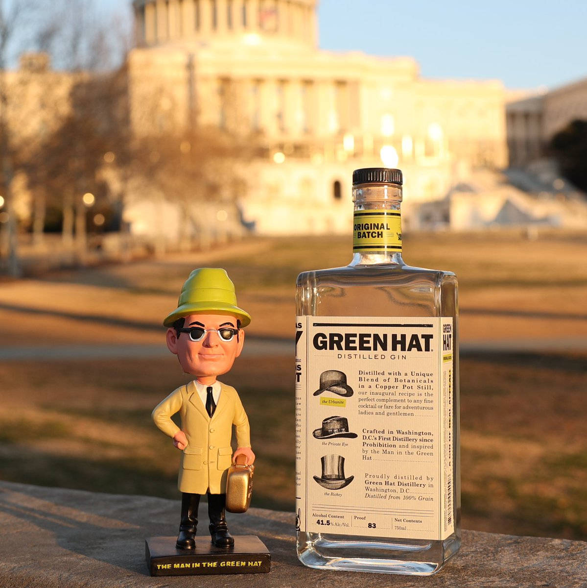 Gin 桌布 壁紙 — 一個「戴綠帽的男人」搖頭娃娃站在美國國會大廈前，旁邊有一瓶 Green Hat Gin，正值黃金時刻。
