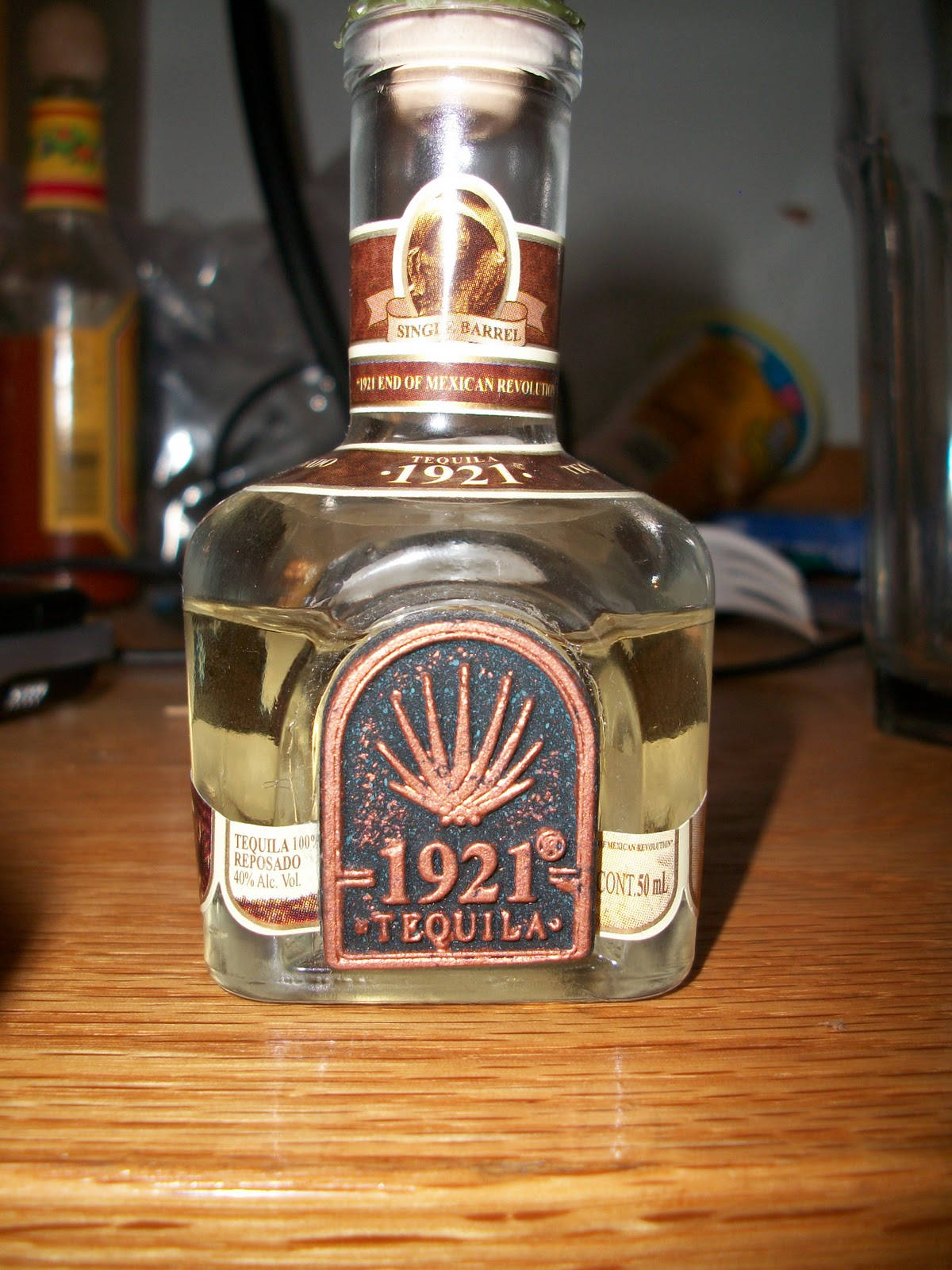 drinks 桌布 壁紙 — 一個1921 Tequila reposado的透明玻璃瓶，置於木質表面中央，周圍有溫暖的環境照明。