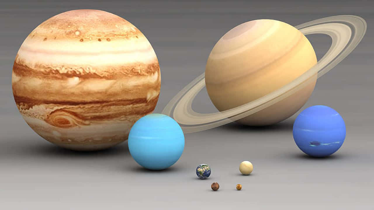 太陽系 桌布 壁紙 — 一個3D渲染的行星排列，包括木星和土星及其光環，排列在一個中性灰色表面上。
