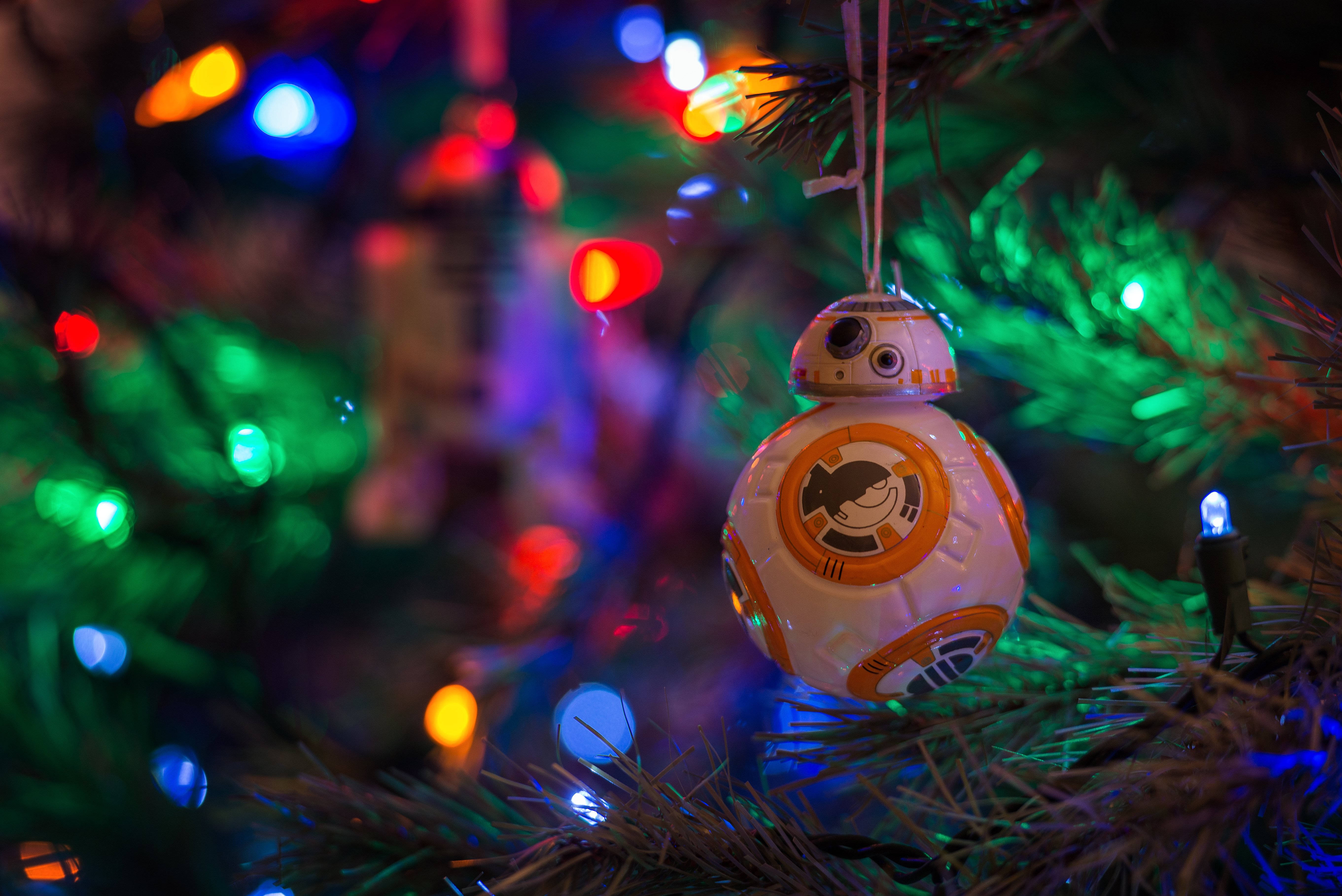 星際大戰 桌布 壁紙 — 一個BB-8機器人裝飾掛在聖誕樹上，周圍是色彩繽紛的散景燈光。