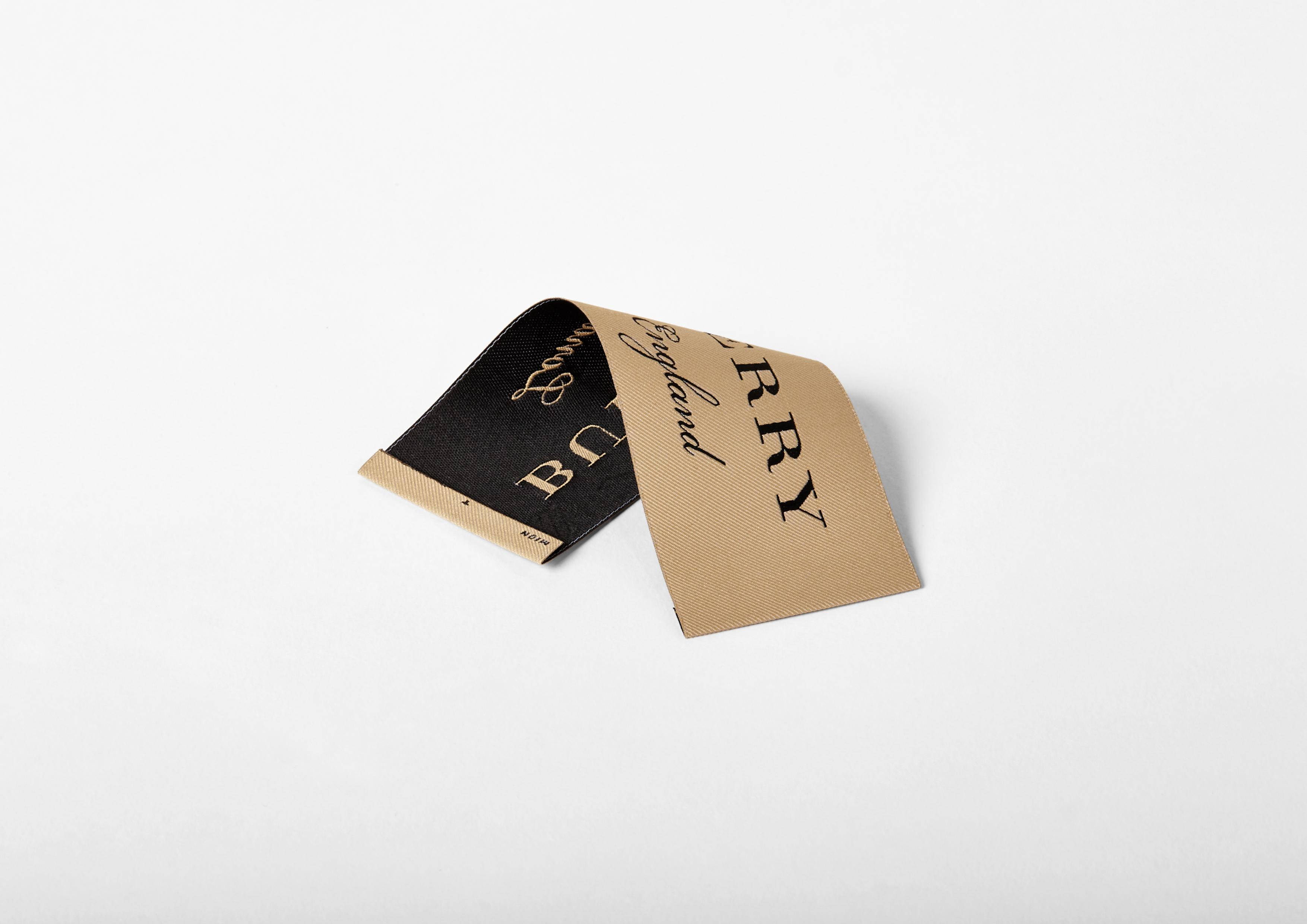 Burberry 桌布 壁紙 — 一個Burberry布料標籤，黑色和米色兩面，摺疊在純白色背景上。