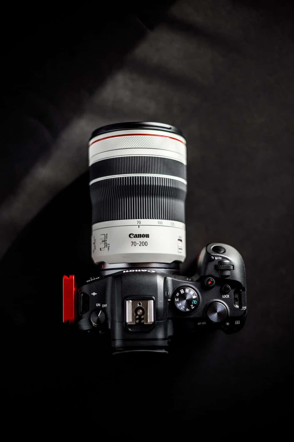 Dslr 桌布 壁紙 — 一個Canon 70-200mm鏡頭安裝在DSLR相機機身上，從上方觀看，背景為深色紋理，帶有戲劇性燈光。