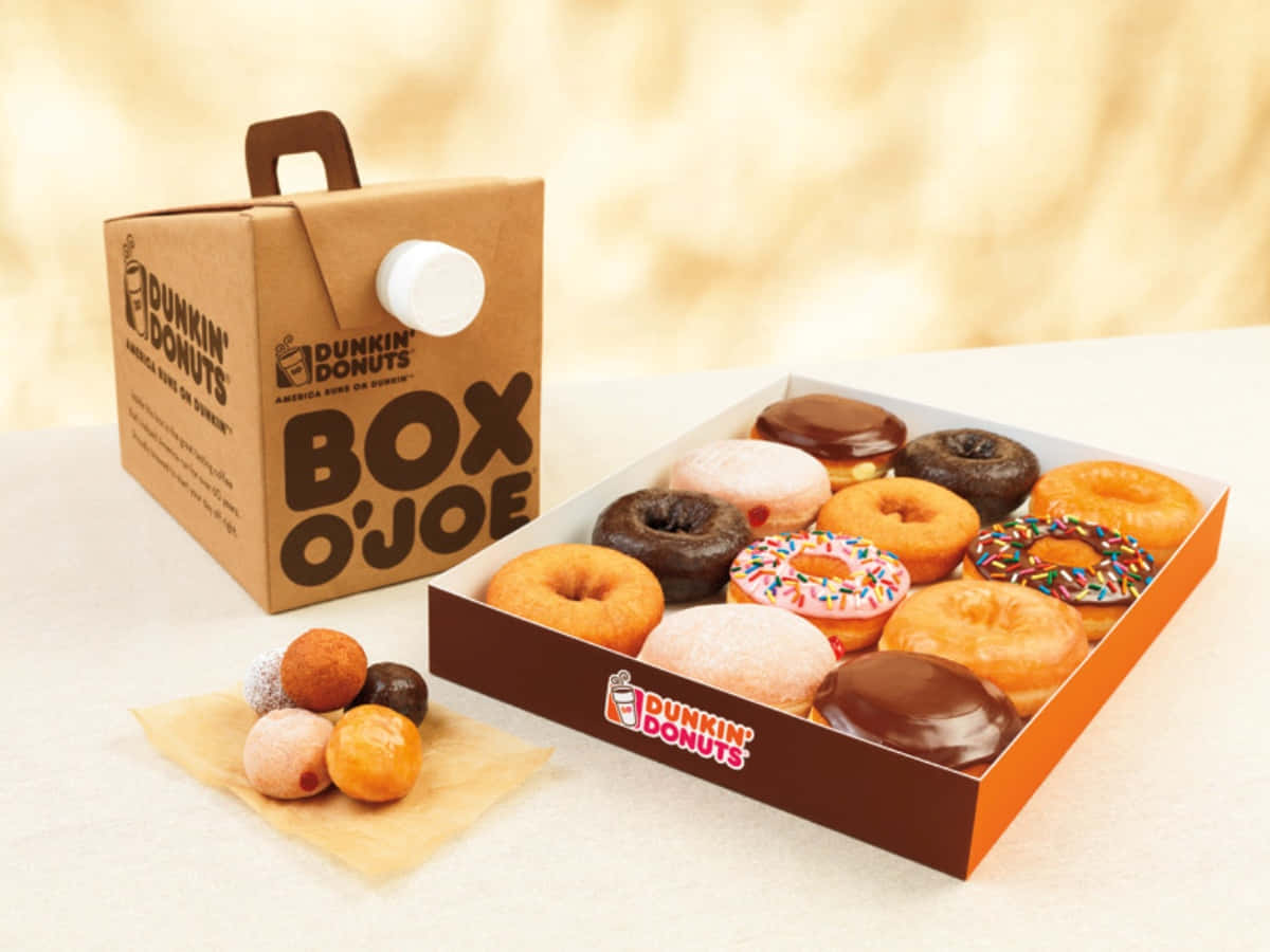 Dunkin Donuts 桌布 壁紙 — 一個Dunkin' Donuts Box O'Joe咖啡盒旁邊放著一盒各式各樣的糖霜和彩針甜甜圈，附近散落著迷你甜甜圈。