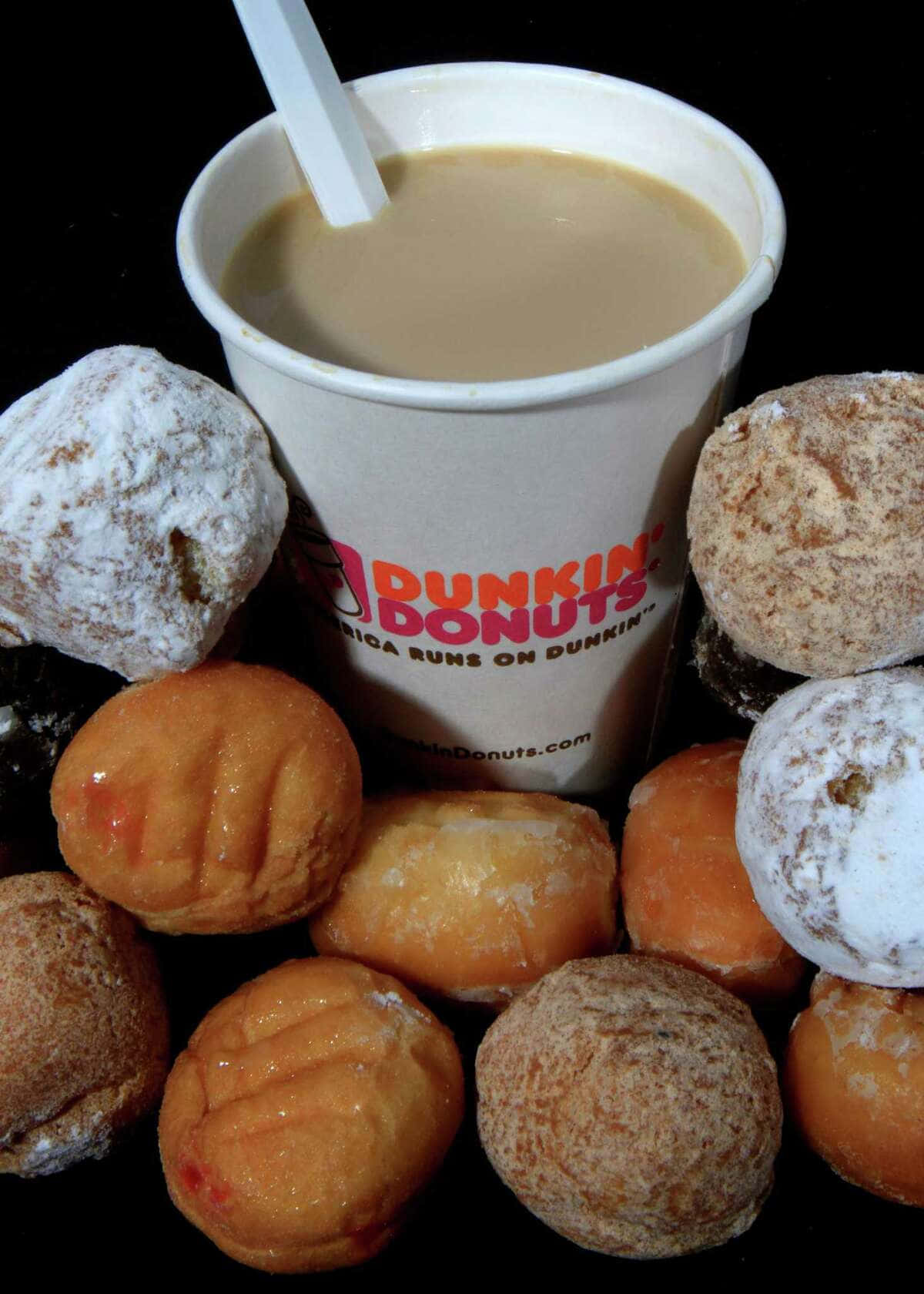 Dunkin Donuts 桌布 壁紙 — 一個Dunkin' Donuts咖啡杯，周圍放滿各種糖霜和糖粉甜甜圈，背景為黑色。