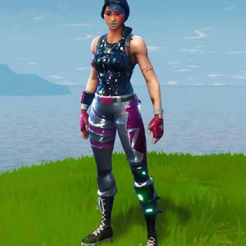 Sparkle Specialist Fortnite 桌布 壁紙 — 一個Fortnite角色自信地站在一個草叢生的懸崖上，俯瞰著平靜的海洋，遠處有山脈，天空清澈湛藍。