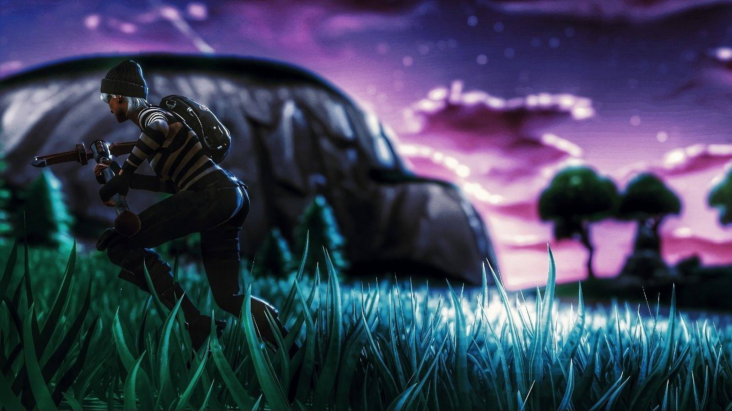Fortnite 桌布 壁紙 — 一個Fortnite角色蹲在發光的藍色草地上，背景是充滿活力的紫色暮色天空，遠處有樹木和一個大型岩石結構。