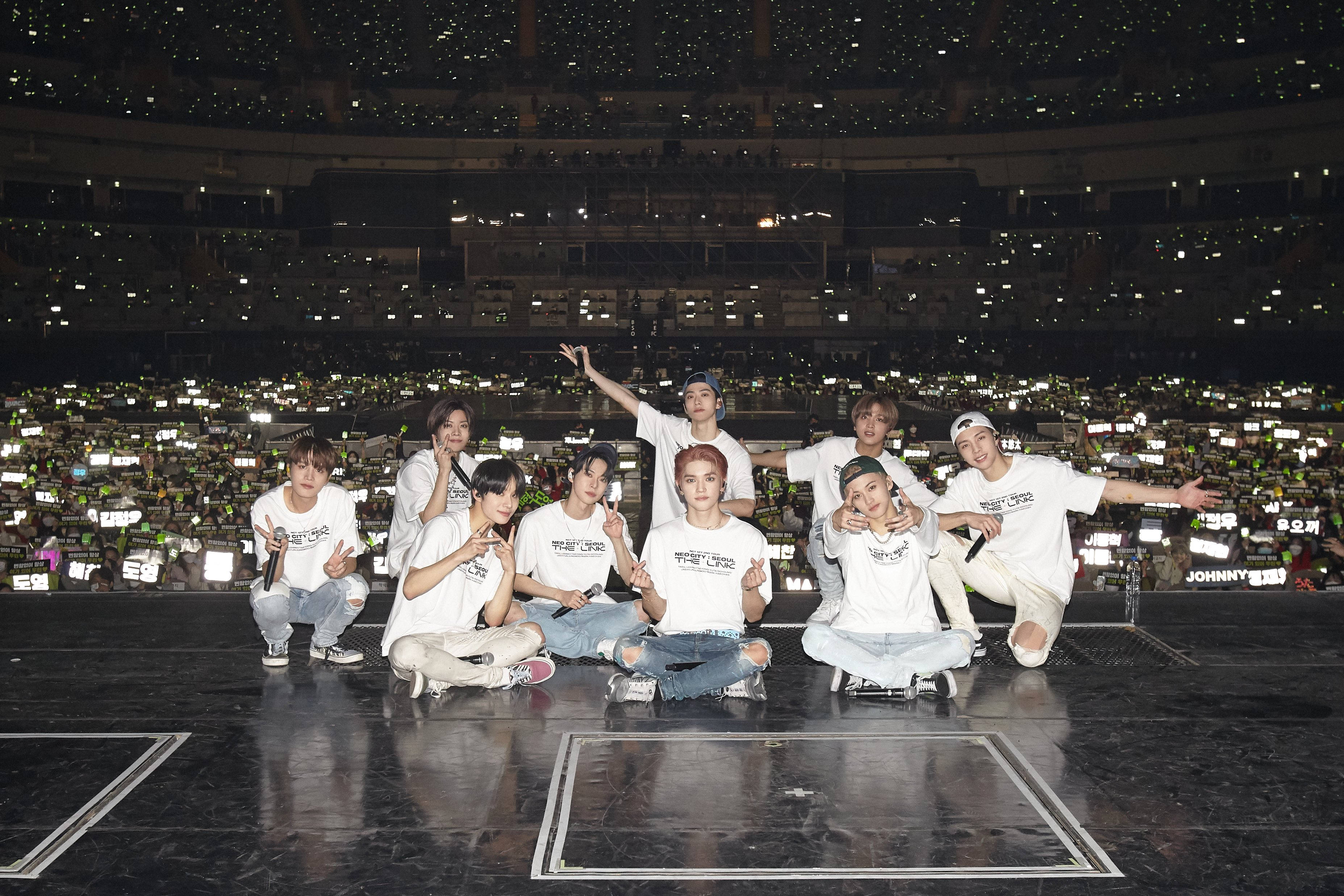 Nct 桌布 壁紙 — 一個K-pop團體在演唱會舞台上擺姿勢，背後是觀眾如海般的綠色手機燈光。