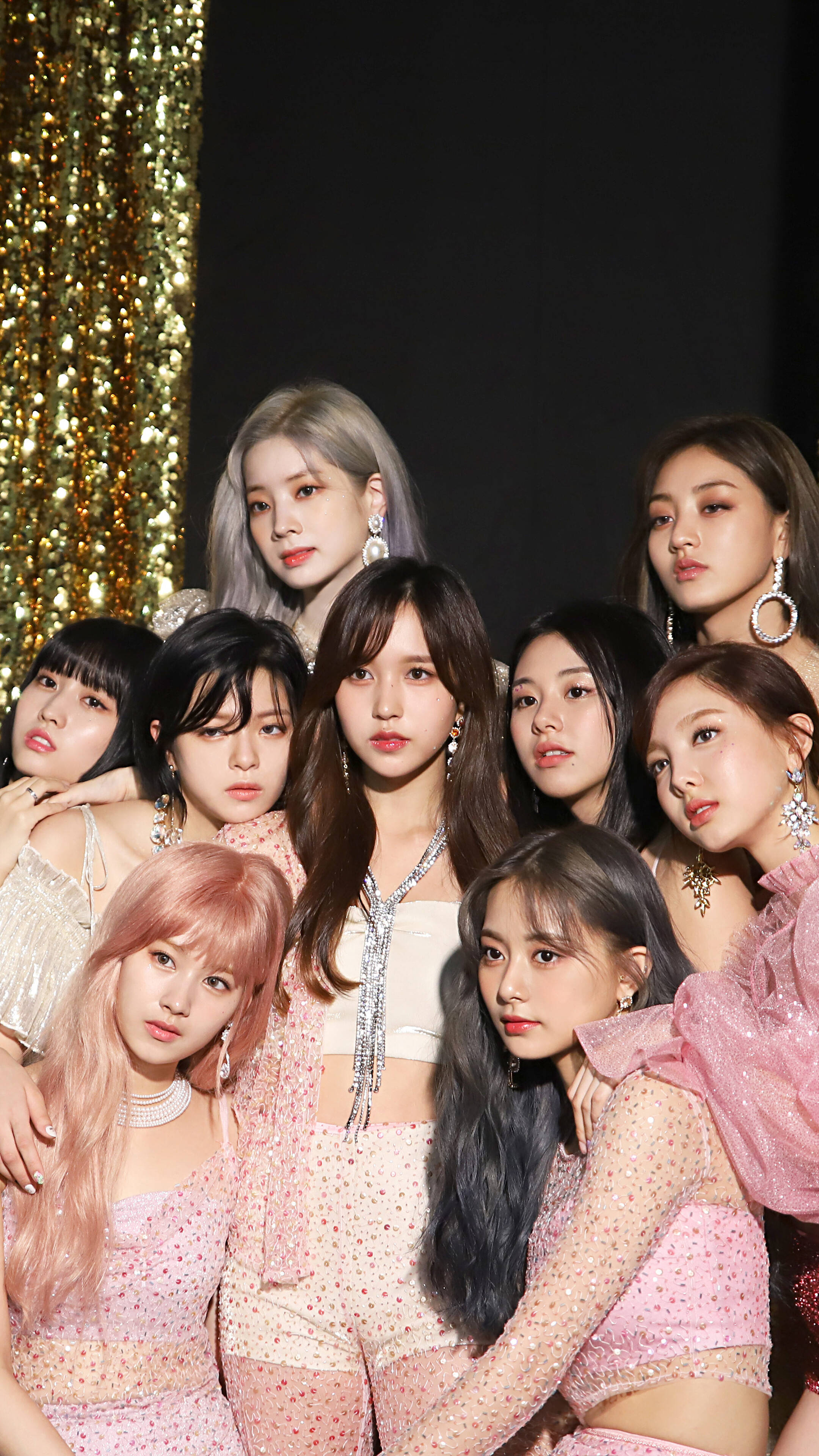 popular phone 桌布 壁紙 — 一個K-pop女團在閃爍的金色背景下自信地擺姿勢，身穿閃亮的粉紅色服裝。
