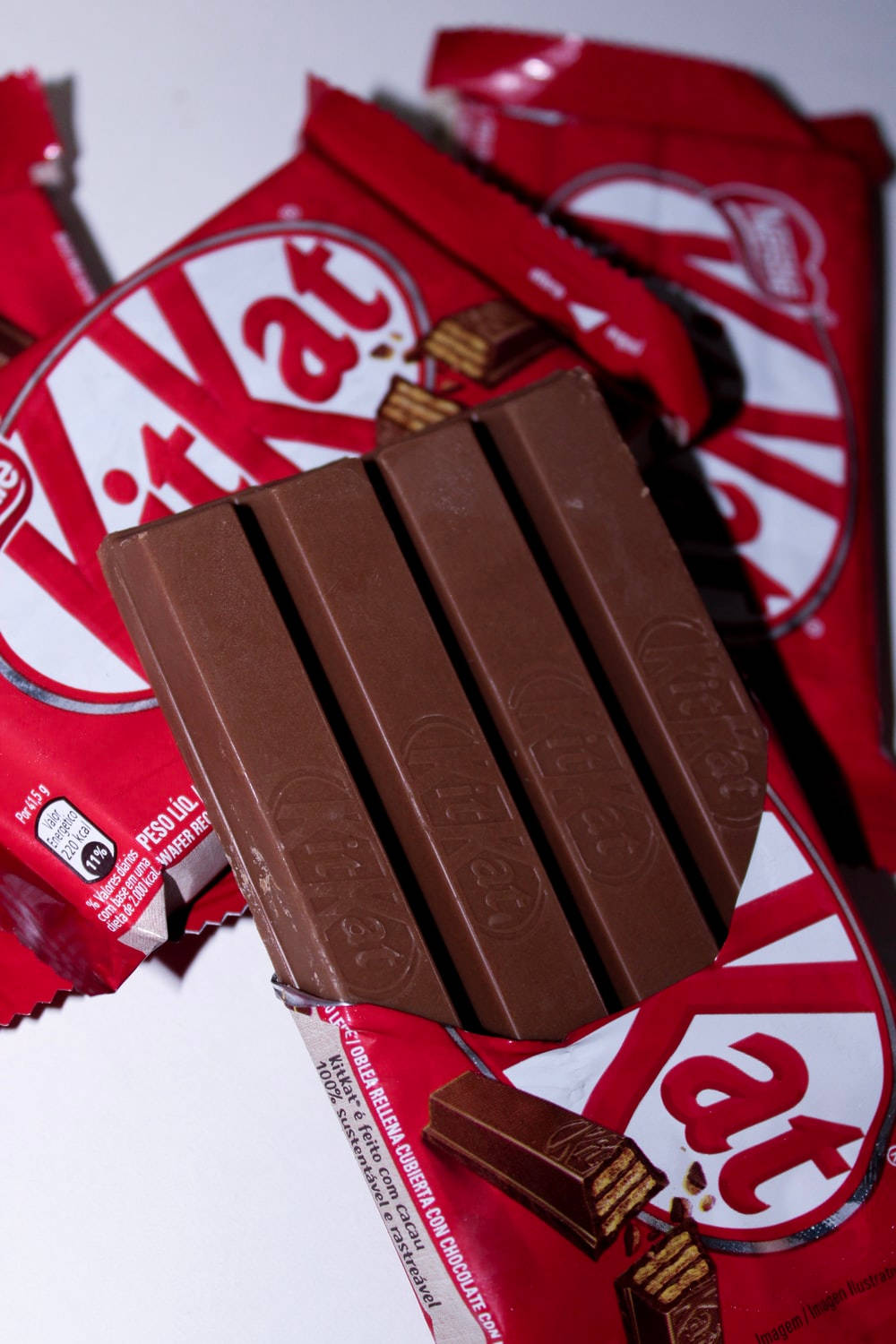 Chocolate 桌布 壁紙 — 一個KitKat巧克力棒的特寫，放在紅色KitKat包裝紙上，細節清晰，棕色色調豐富。