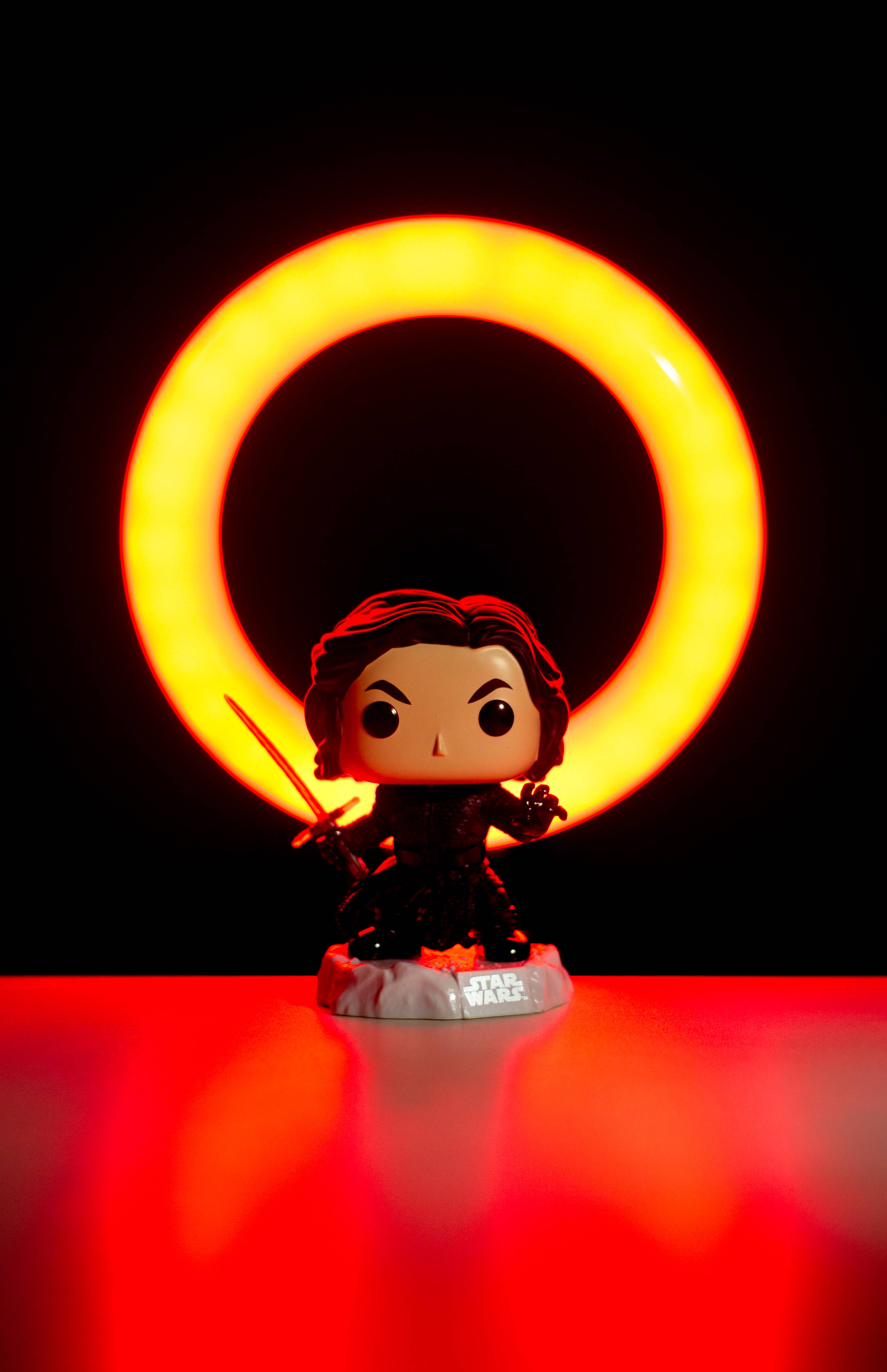 Funko Pop 桌布 壁紙 — 一個Kylo Ren的Funko Pop!人偶站在發光的橙色環前，背景為黑色，下方有紅色反射。