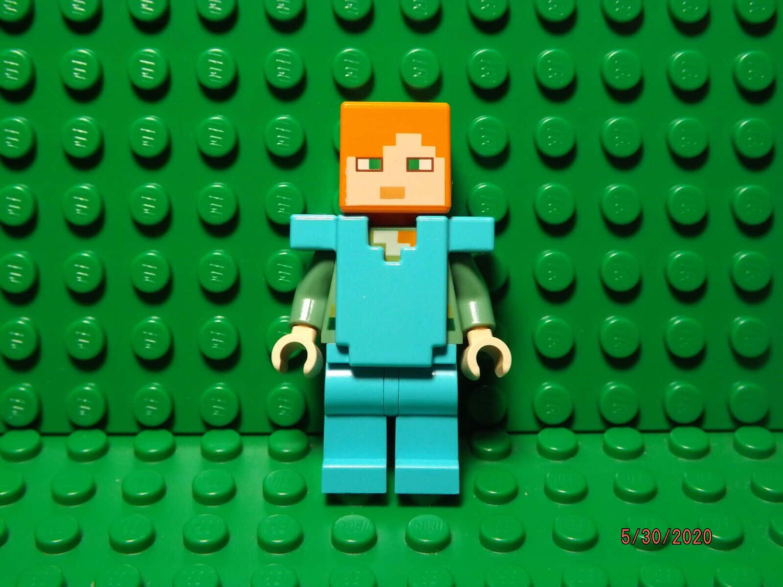 Minecraft Armor 桌布 壁紙 — 一個Lego Minecraft角色在充滿活力的綠色Lego磚牆背景前居中站立。
