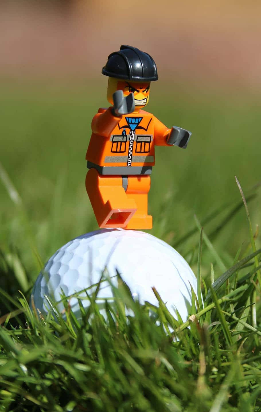 高爾夫 桌布 壁紙 — 一個LEGO建築工人迷你人偶勝利地站在一顆嵌在鮮綠色草地上的白色高爾夫球上。