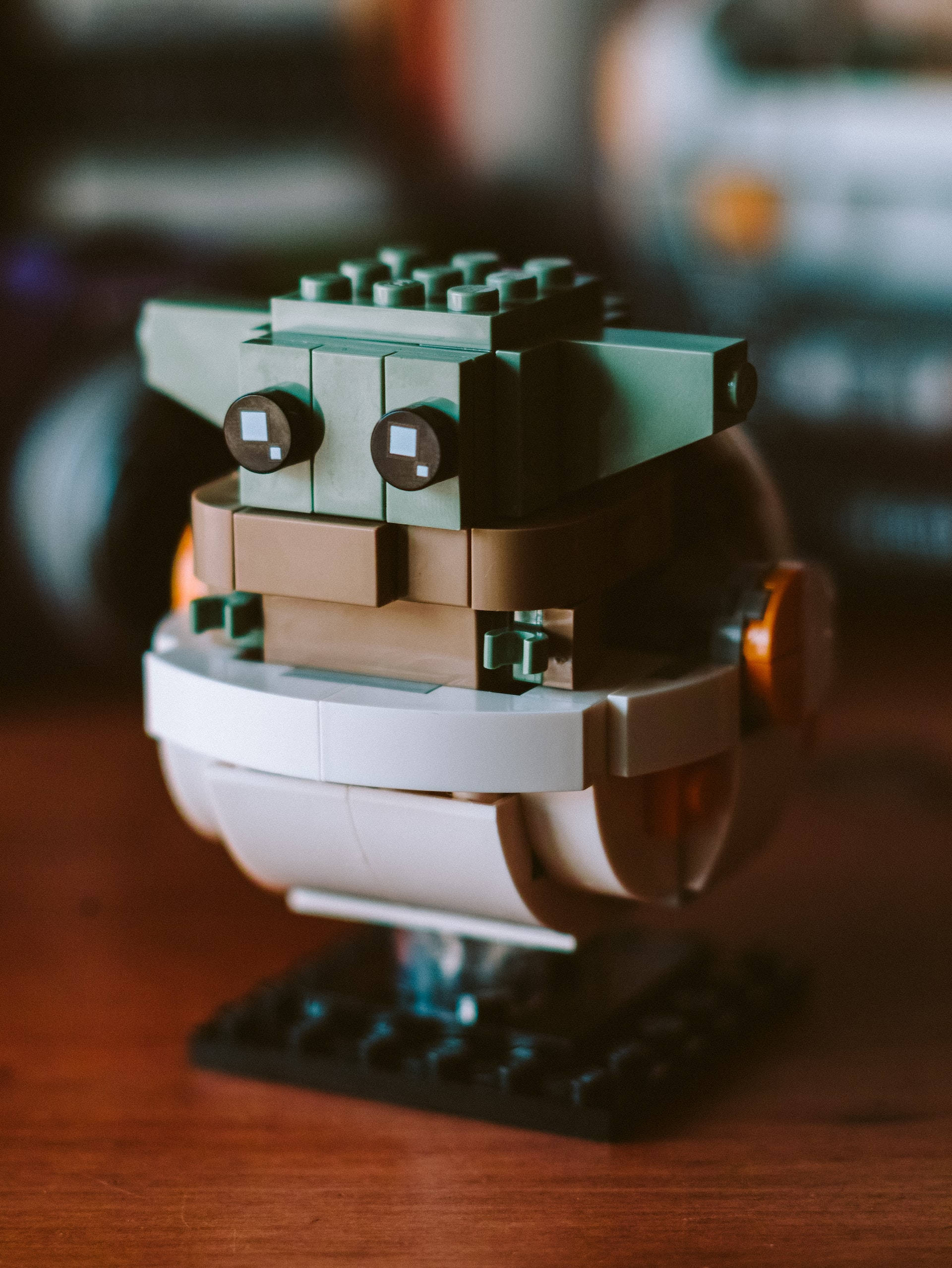 星際大戰 iPhone 桌布 壁紙 — 一個LEGO星際大戰古古迷你人偶的特寫，有大眼睛和綠色皮膚，坐在木質表面上。