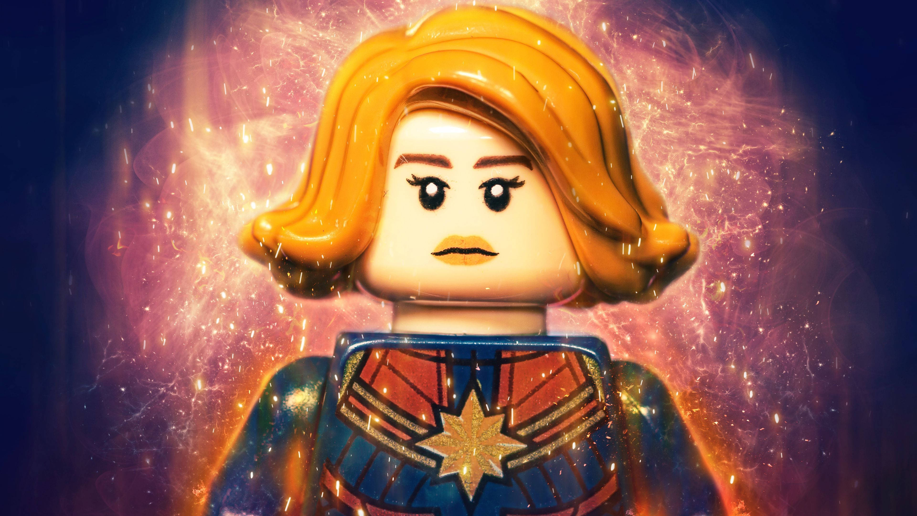 樂高 桌布 壁紙 — 一個LEGO驚奇隊長人偶散發出宇宙能量，發光粒子在她標誌性的星形徽章服裝周圍旋轉。