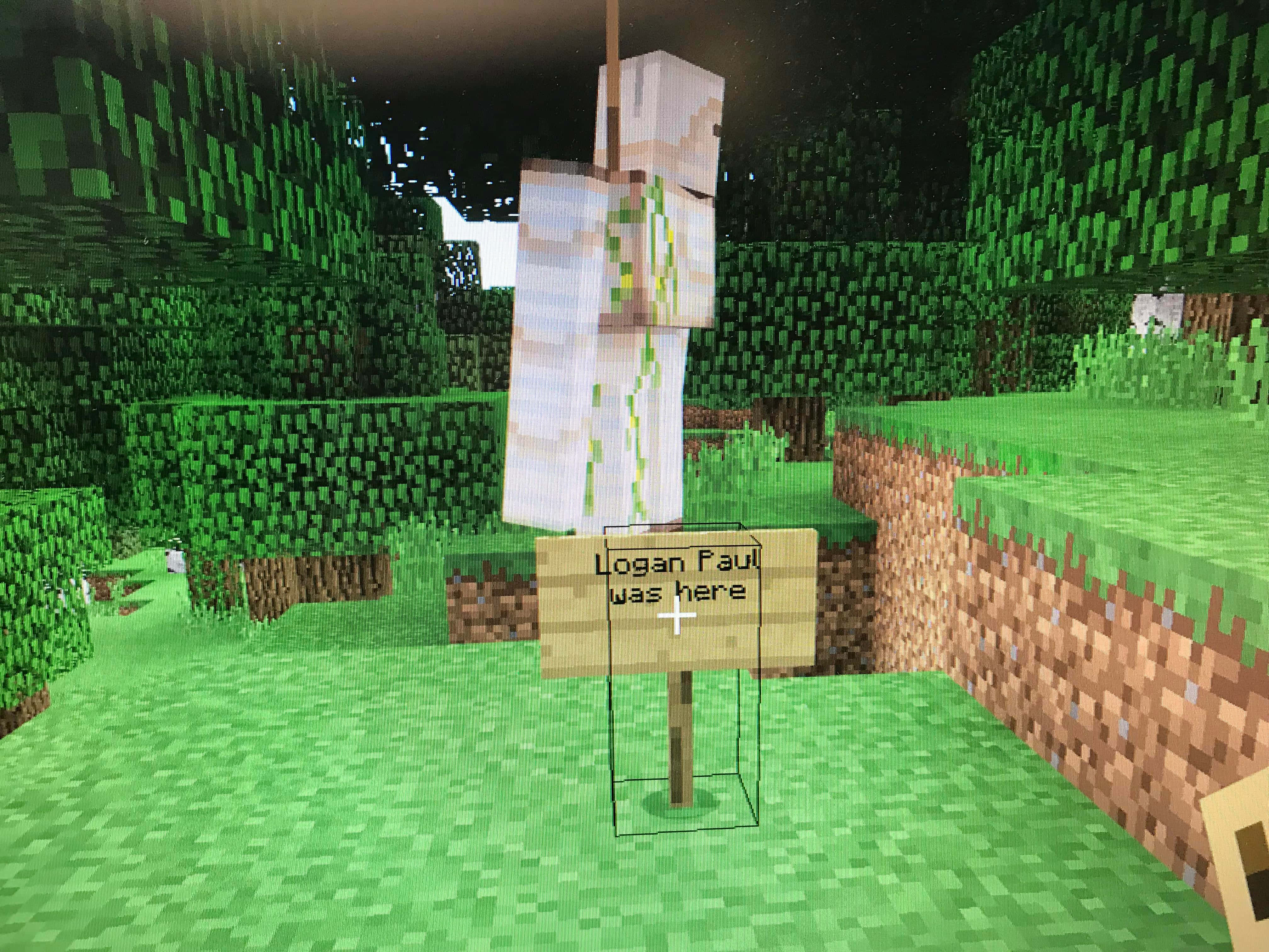 Minecraft Education Edition 桌布 壁紙 — 一個Minecraft角色在夜晚的像素化森林中站在一個寫著Logan Paul was here的標誌旁邊。