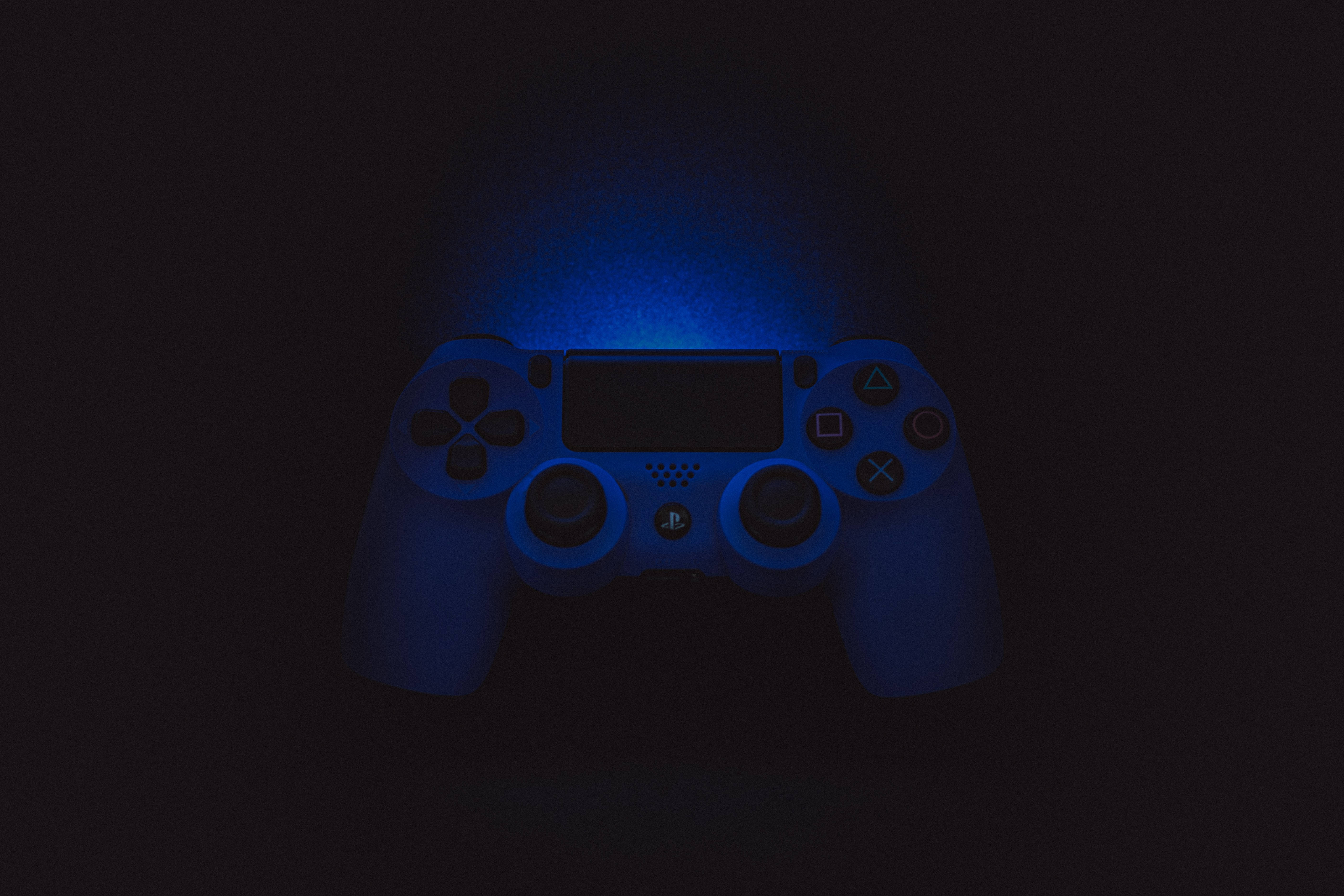 Best Ps4 桌布 壁紙 — 一個PlayStation手把在漆黑背景中發出鮮豔的藍光。