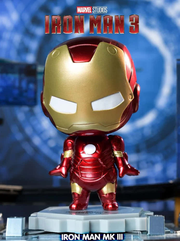 Iron Man Bobbleheads 桌布 壁紙 — 一個Q版風格的鋼鐵人MK III可動人偶站在灰色底座上，背景是藍色科技主題並帶有電影標題文字。
