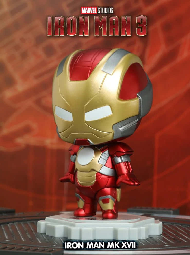 Iron Man Bobbleheads 桌布 壁紙 — 一個Q版風格的鋼鐵人MK XVII人偶站在齒輪底座上，背景是紅色科技主題和電影標題文字。