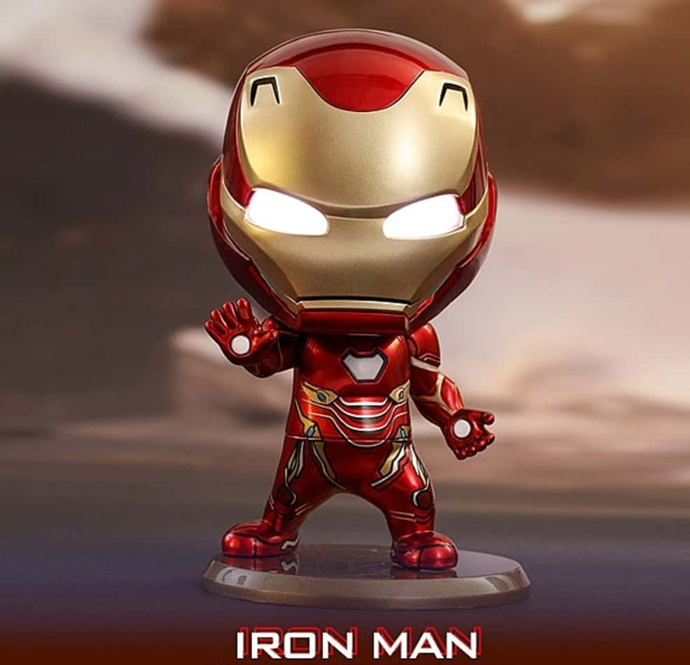 Iron Man Bobbleheads 桌布 壁紙 — 一個Q版風格的鋼鐵人可動人偶，帶有發光的眼睛和斥力手，站在底座上，背景是模糊的沙漠。