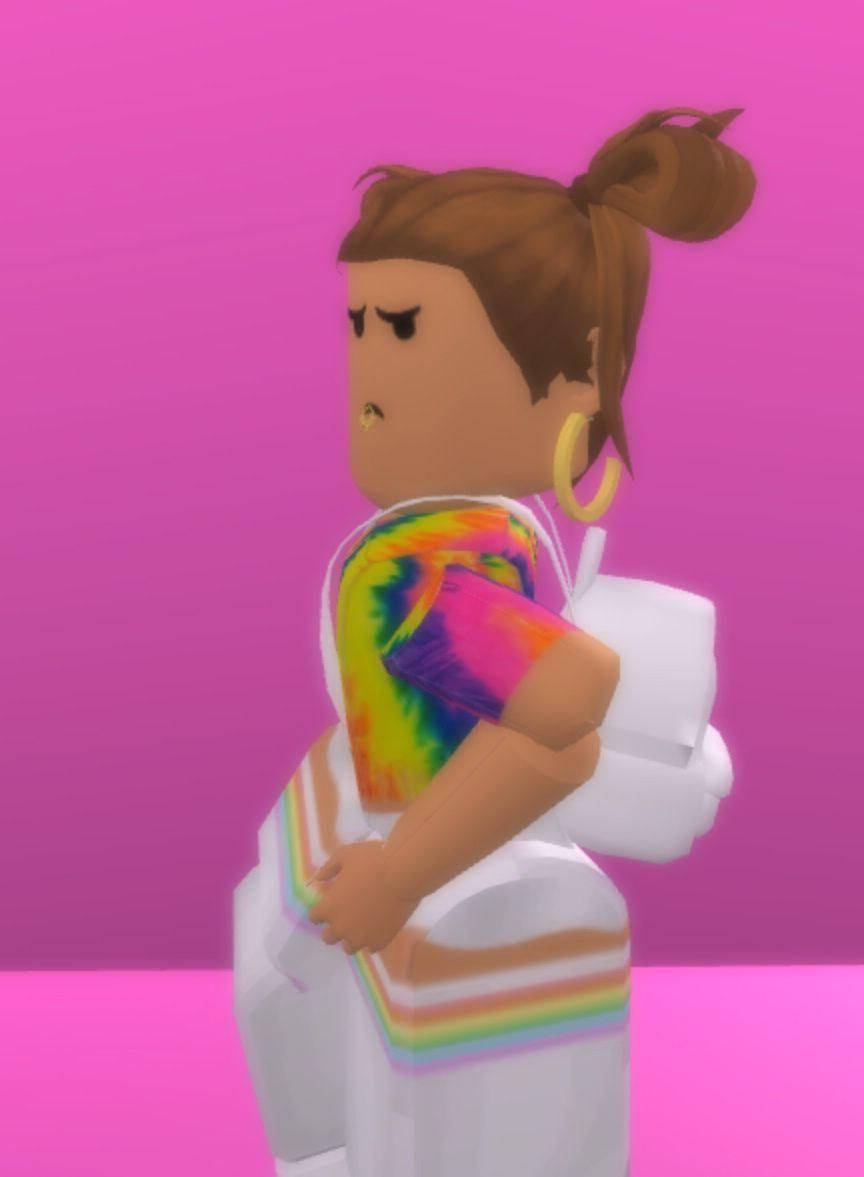 Roblox 桌布 壁紙 — 一個Roblox頭像，棕色頭髮盤成髮髻，穿著紮染襯衫和彩虹條紋褲子，背景為純粉色。
