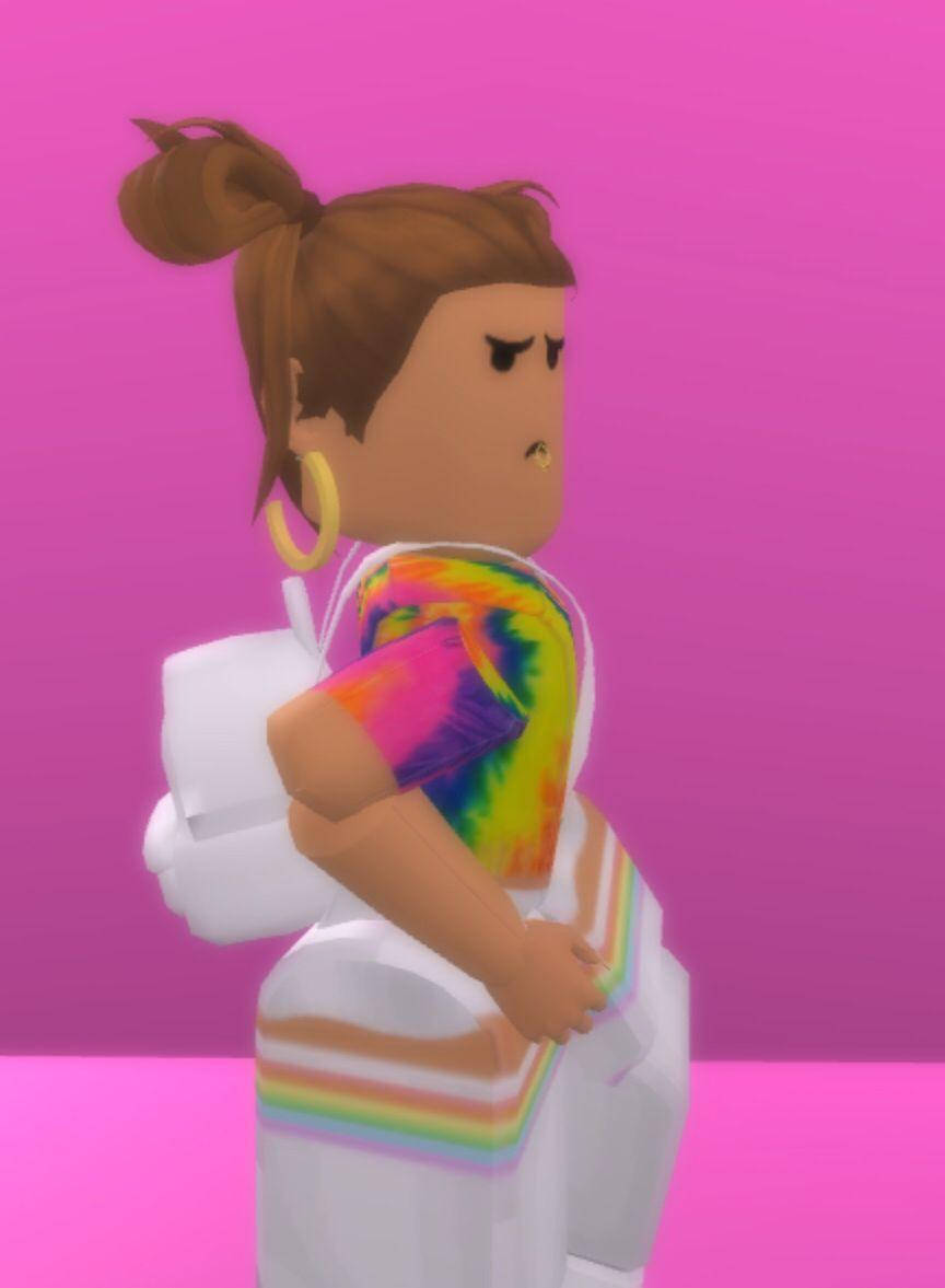 Roblox 桌布 壁紙 — 一個Roblox頭像，棕色頭髮紮成髮髻，穿著彩虹紮染襯衫和彩虹條紋褲子，背景為純粉紅色。