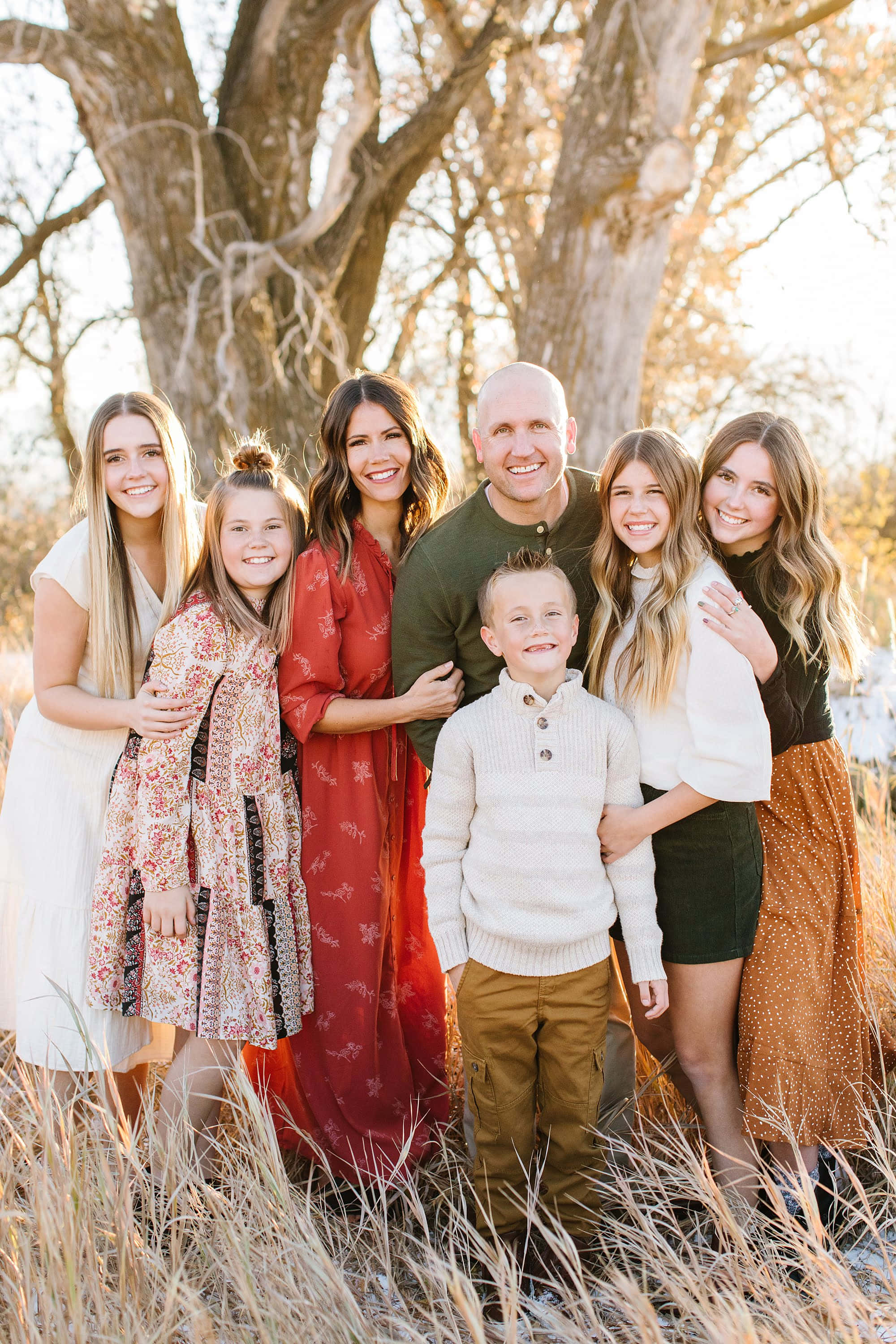 Fall Family 桌布 壁紙 — 一個七人微笑家庭在金色午後陽光下，被高高的乾草包圍，在一棵大樹下一起擺姿勢。