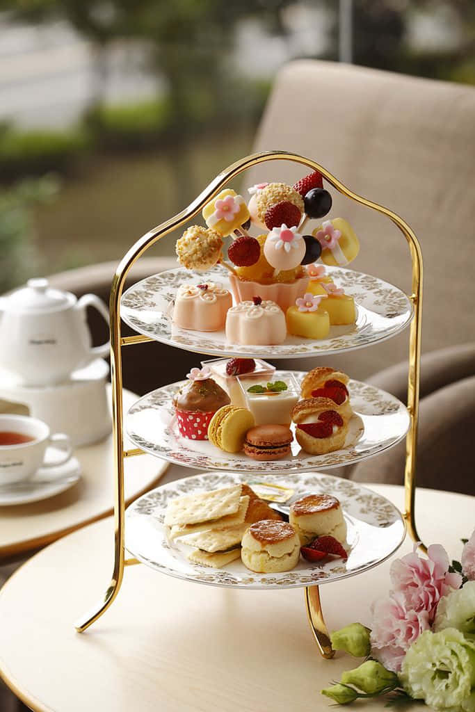 Teatime 桌布 壁紙 — 一個三層金色架子上擺放著精緻的糕點、馬卡龍、司康和水果甜點，為優雅的下午茶而設。